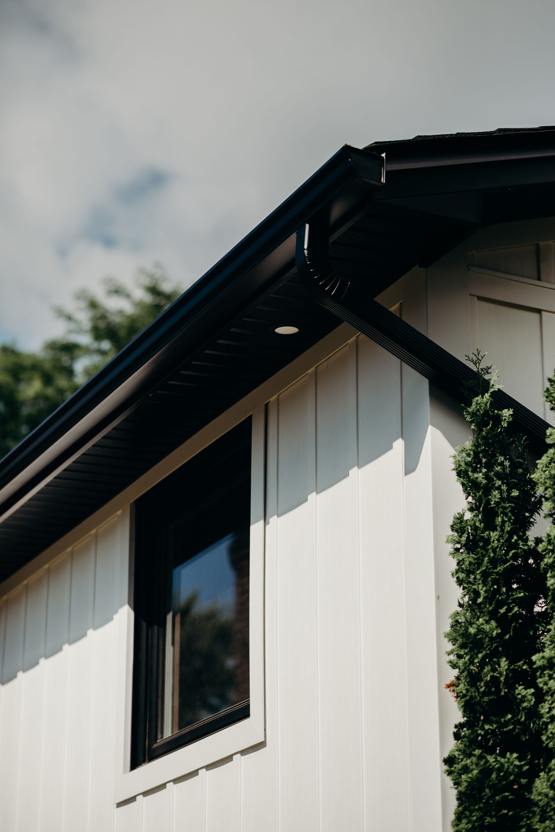 A white house with a black gutter and a window.