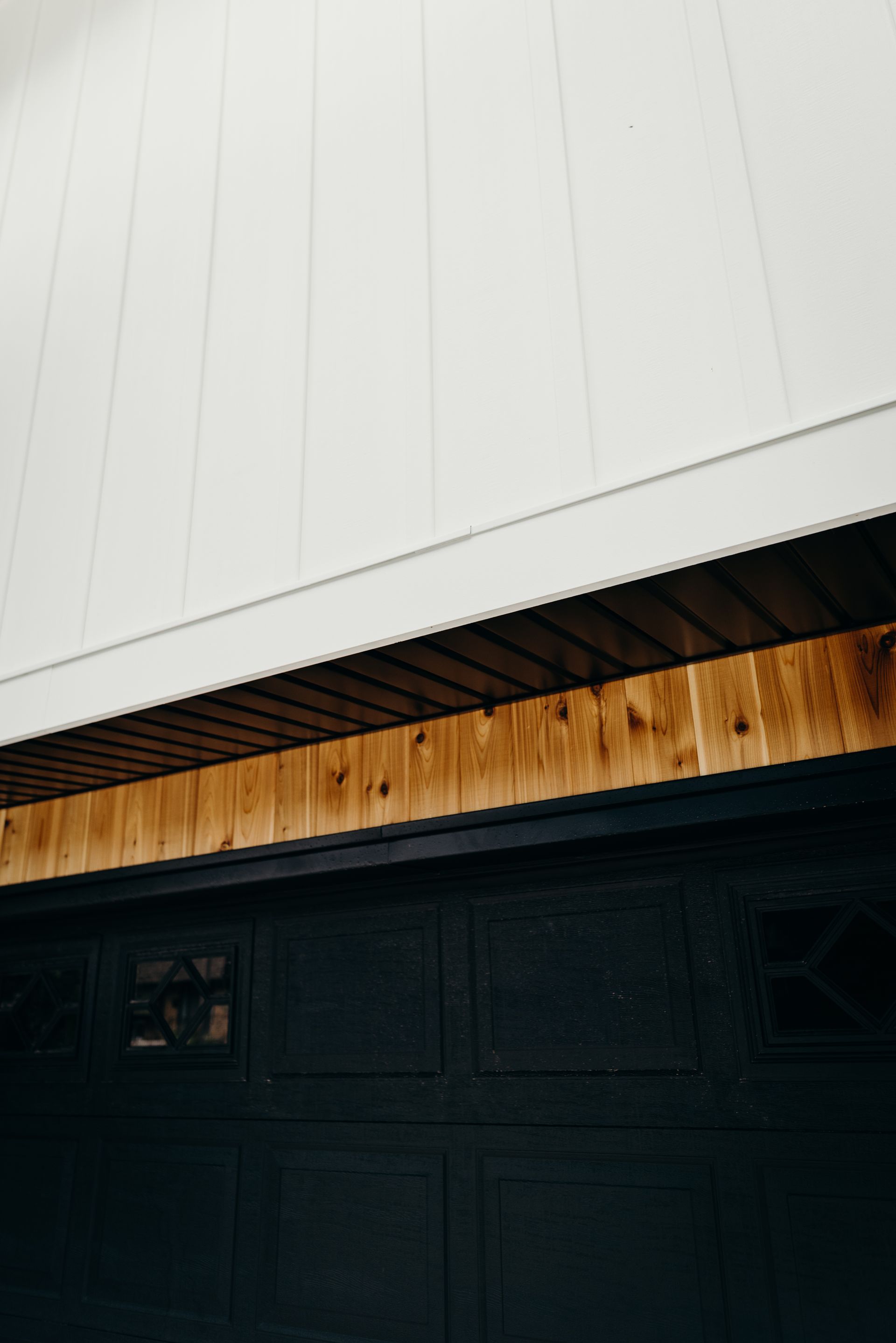 A black garage door with a white roof and wooden trim.