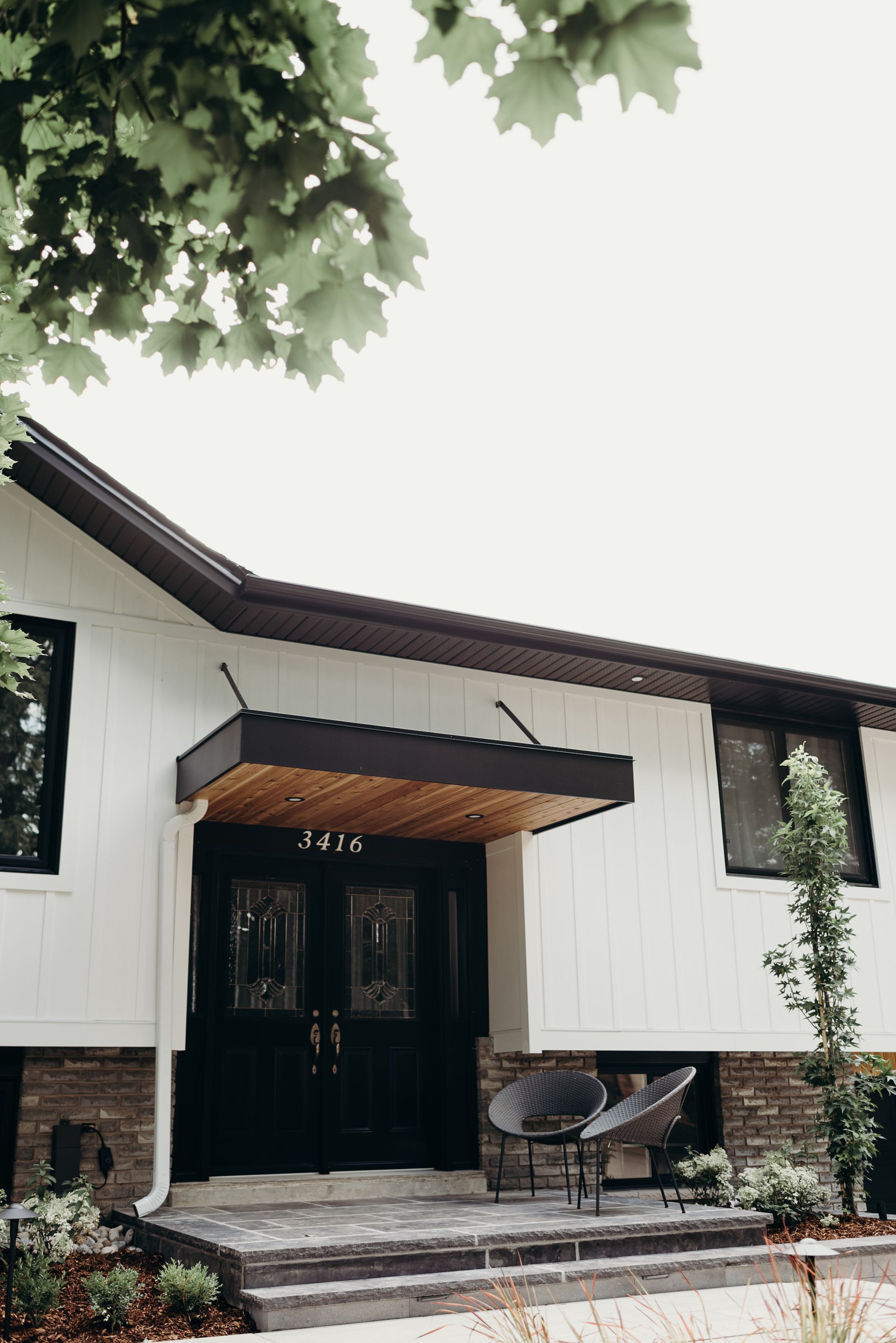 A white house with a black door and a canopy over the front door.