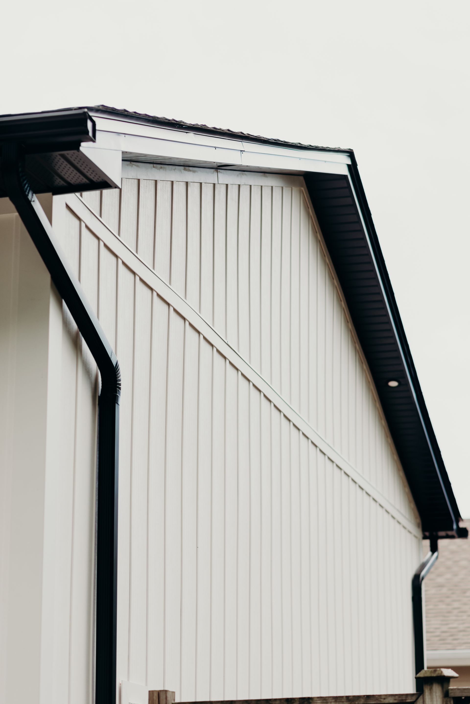 A white house with a black gutter on the side of it.