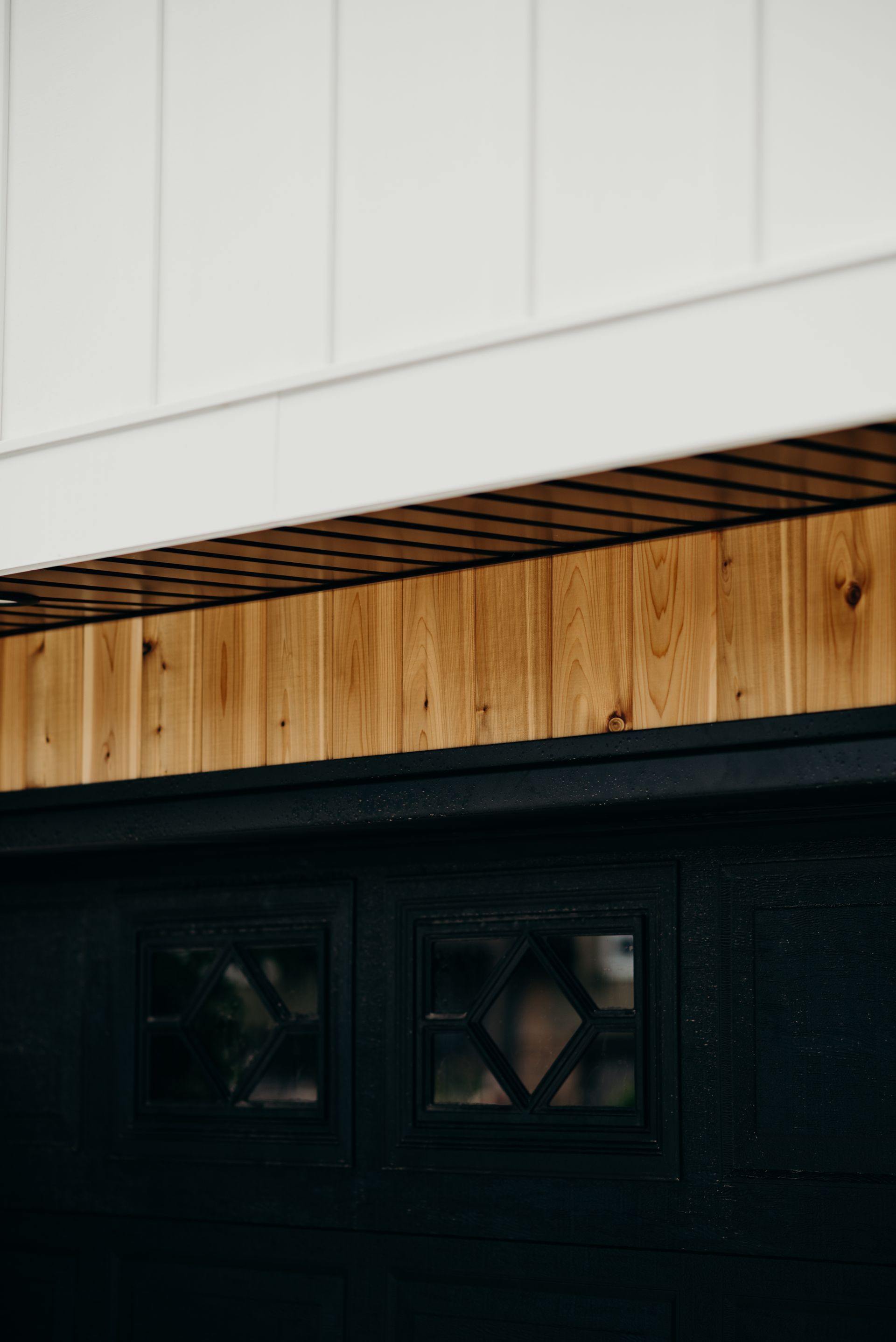 A close up of a black garage door with a wooden ceiling.