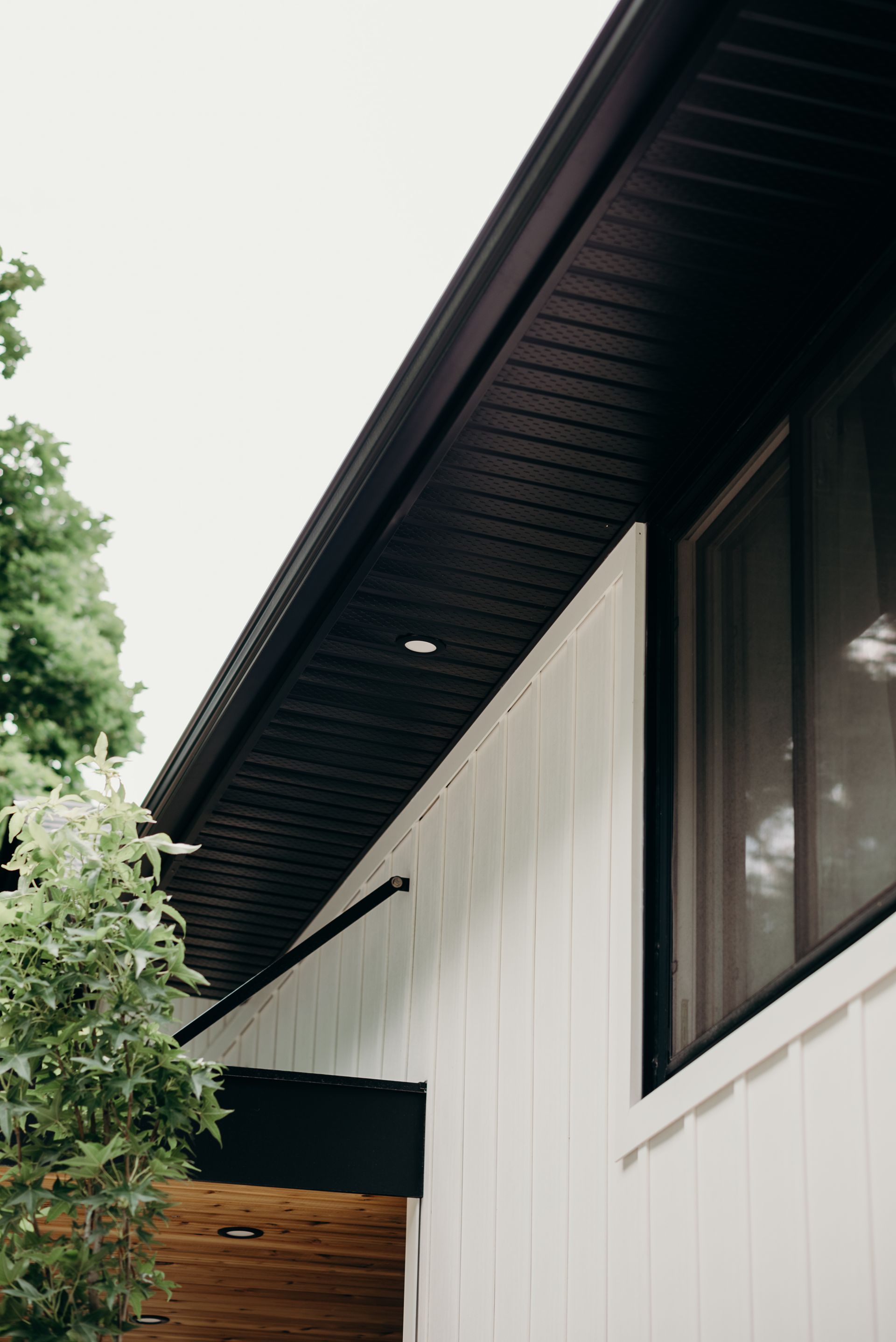 A white house with a black gutter and a window.