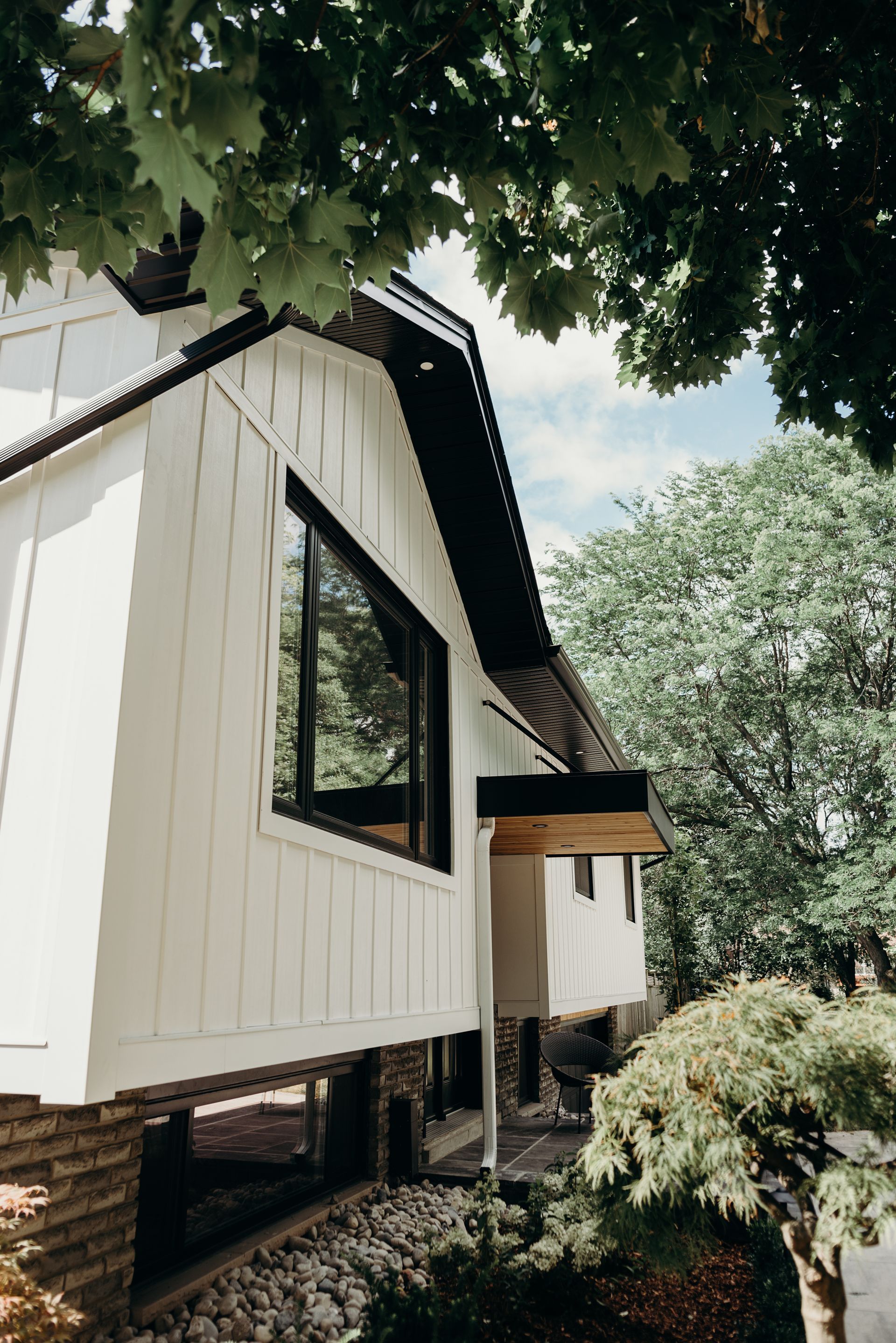 A white house with a black roof is surrounded by trees.