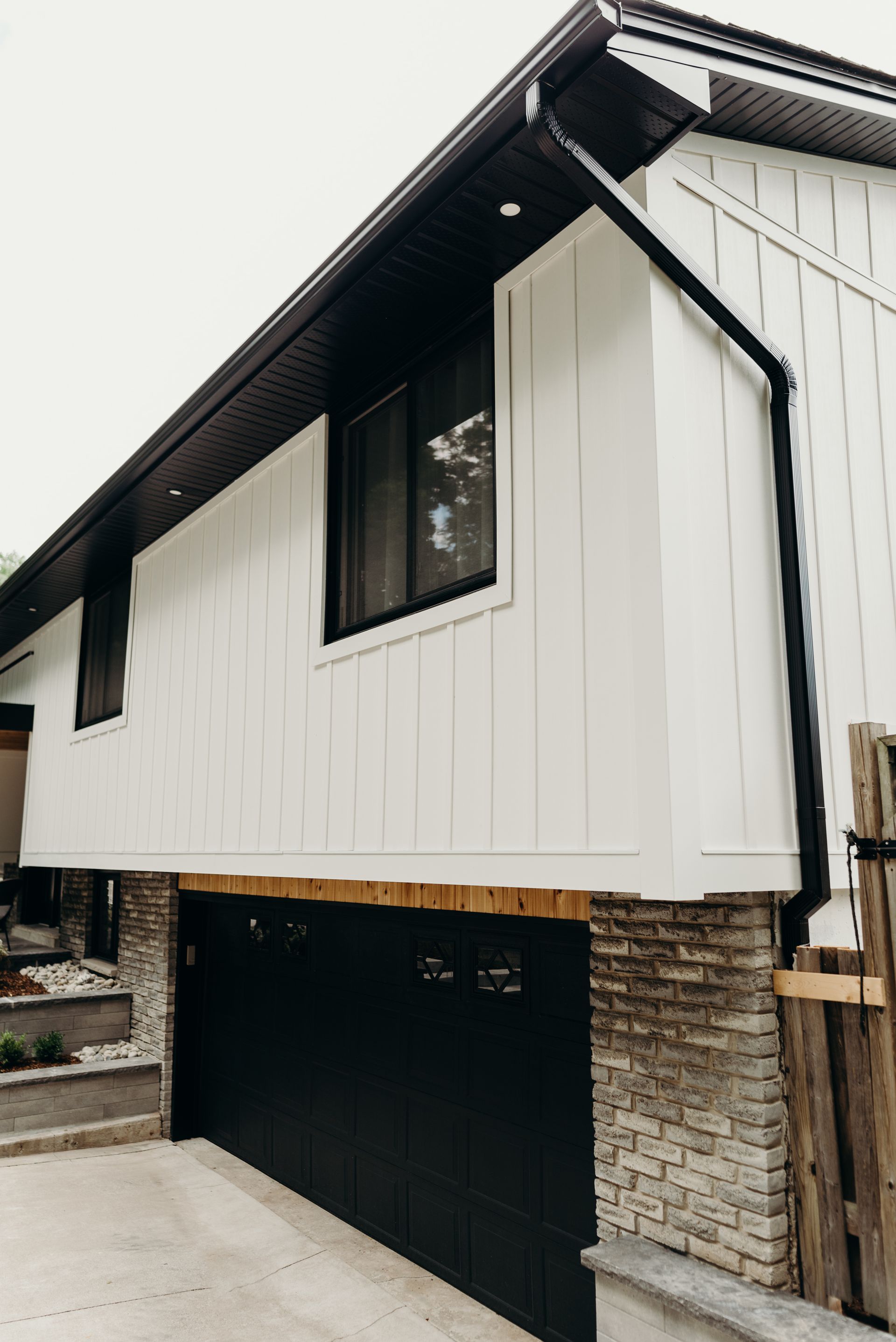 A white house with a black garage door and a black gutter.