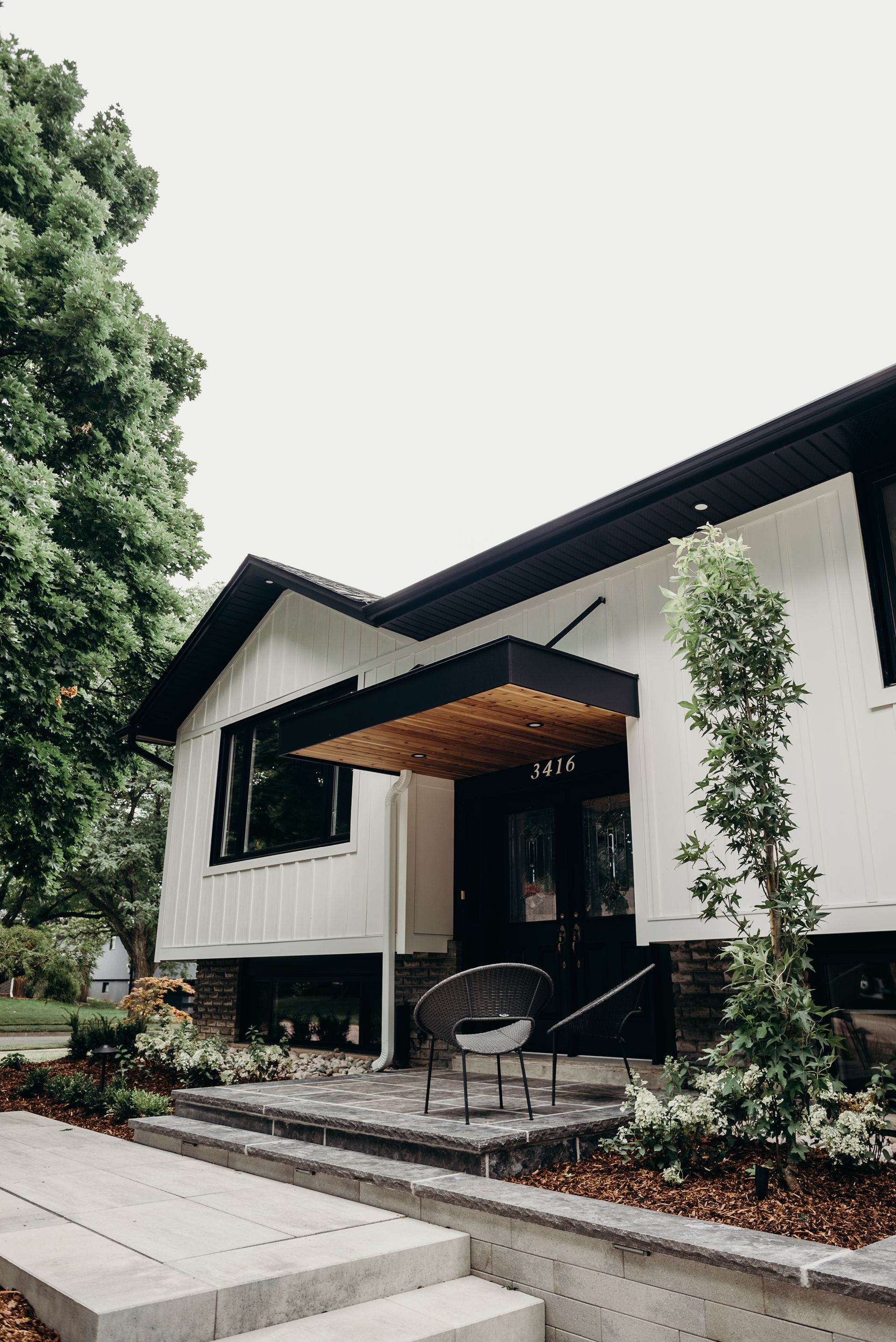 A white house with a black roof and a porch.