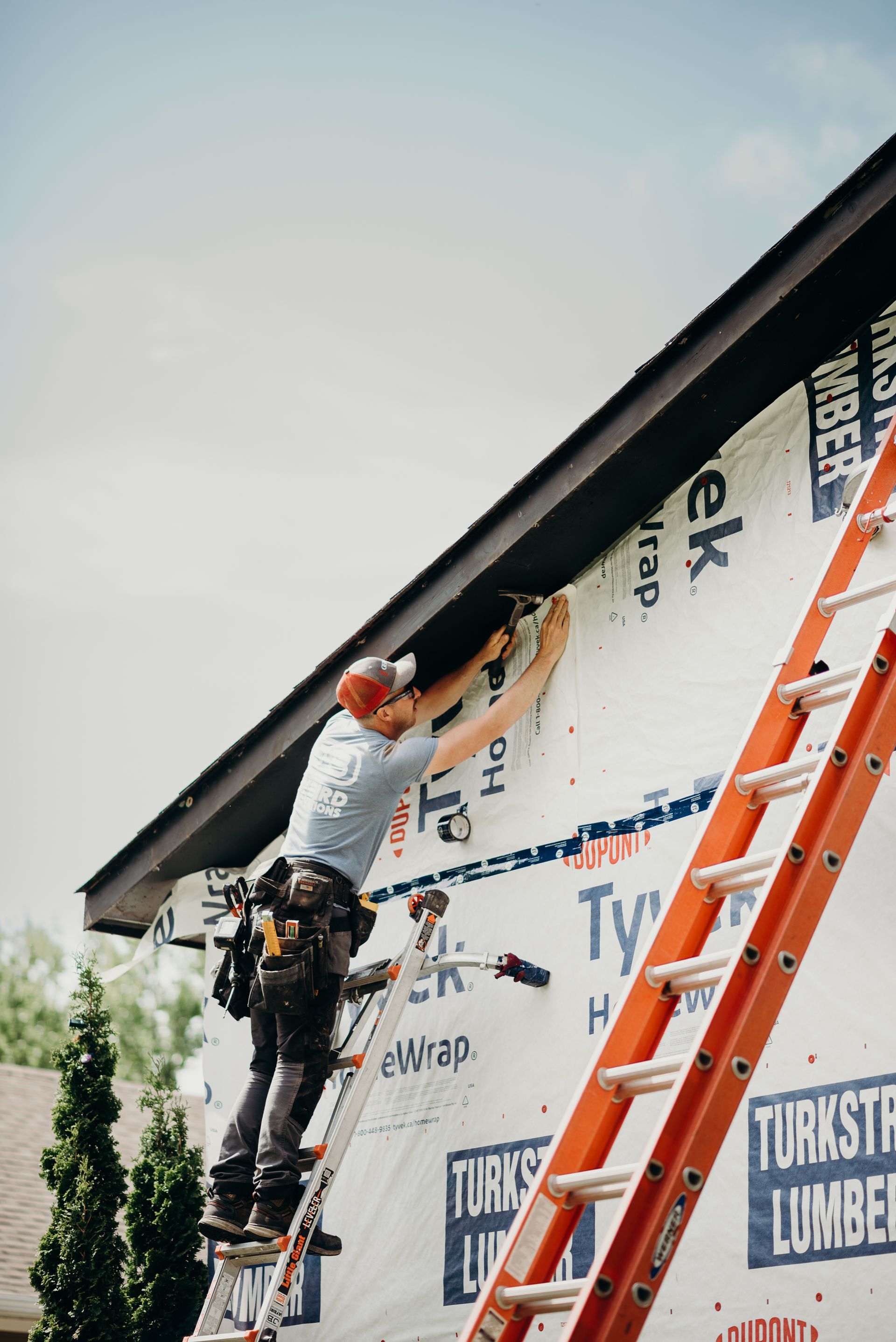 A man is standing on a ladder on the side of a building.