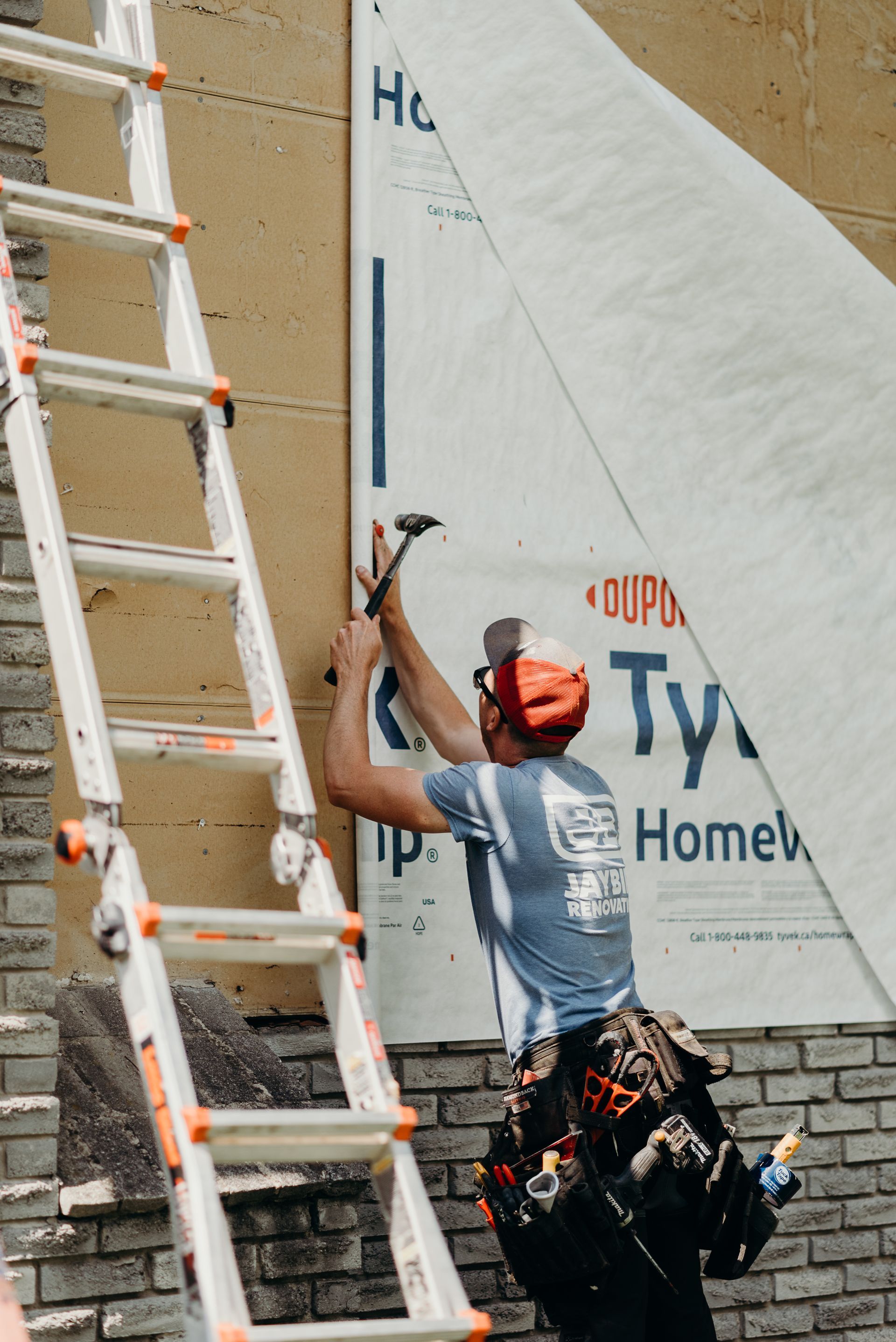 A man is standing on a ladder working on a wall.