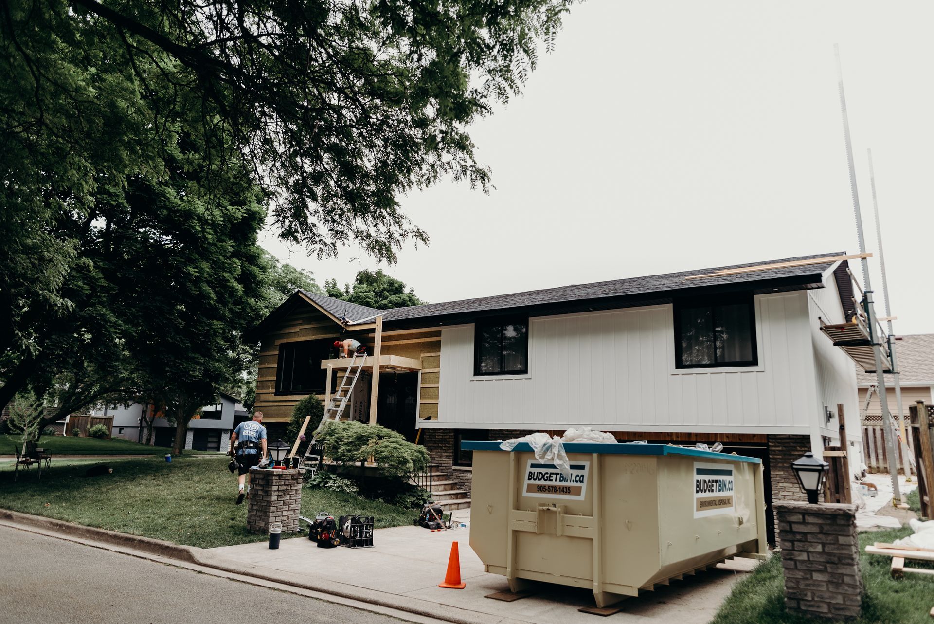 A house is being remodeled with a dumpster in front of it.