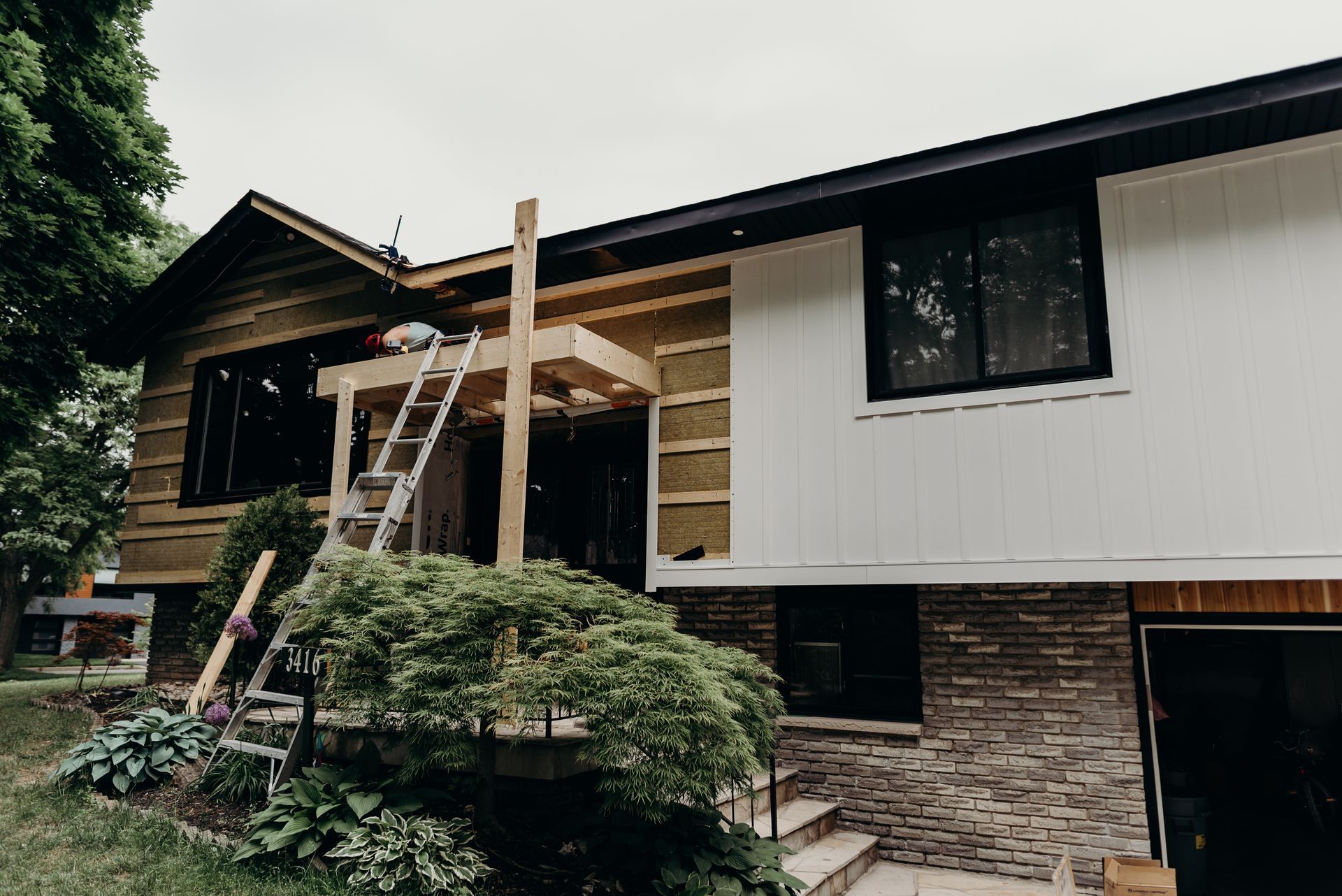 A house with a ladder on the side of it is being remodeled.
