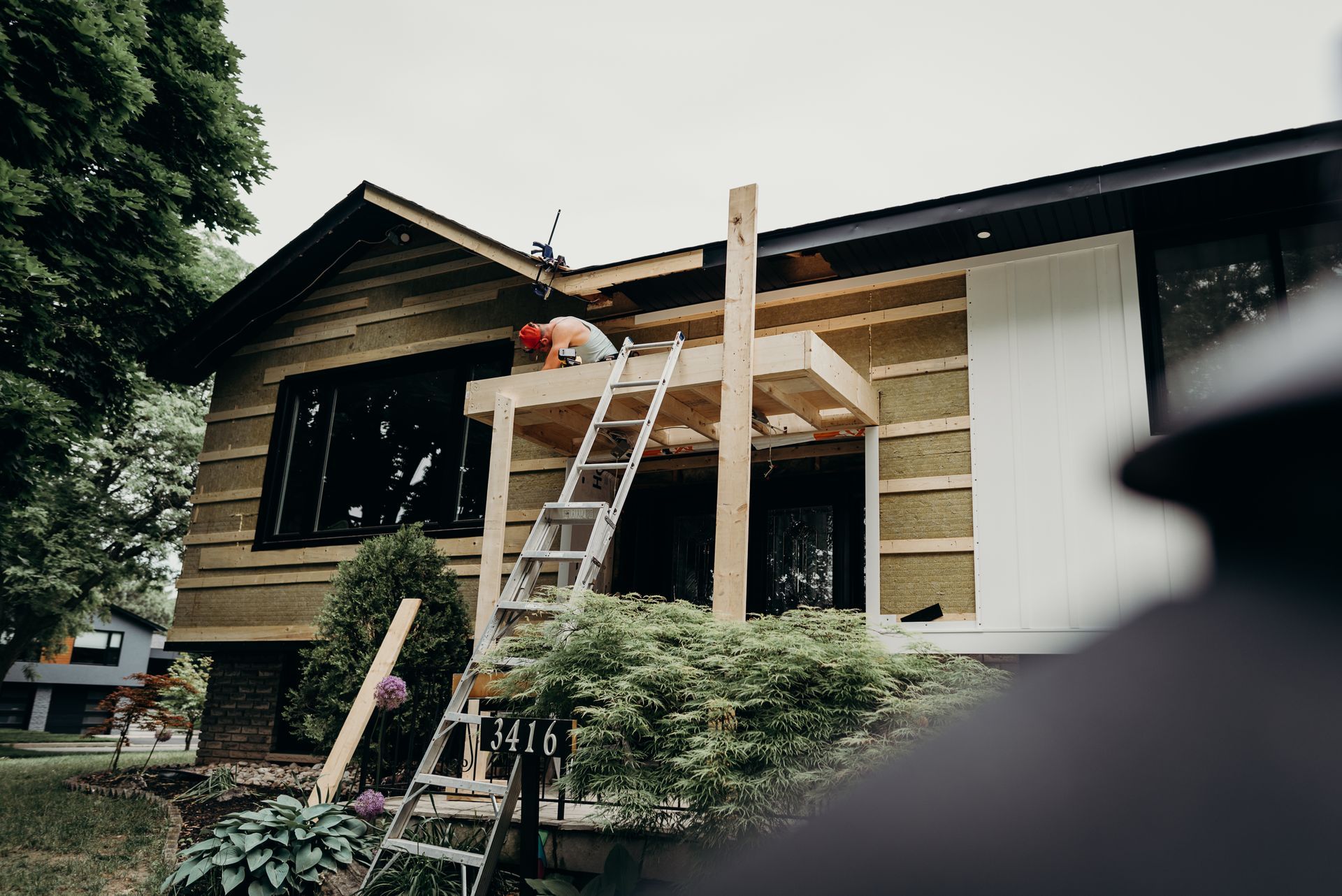 A man on a ladder is working on the side of a house.