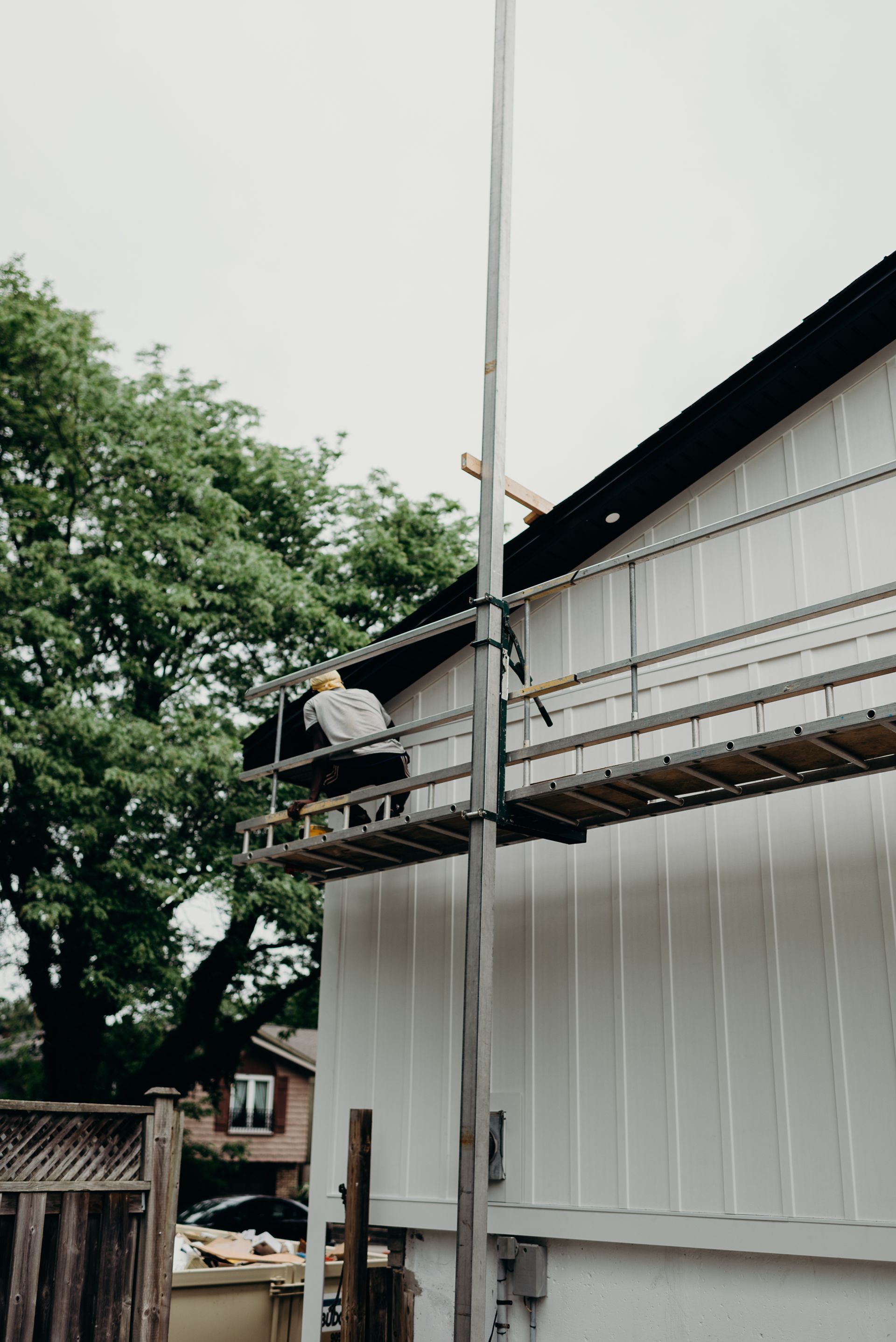 A man is standing on a ladder on the side of a building.