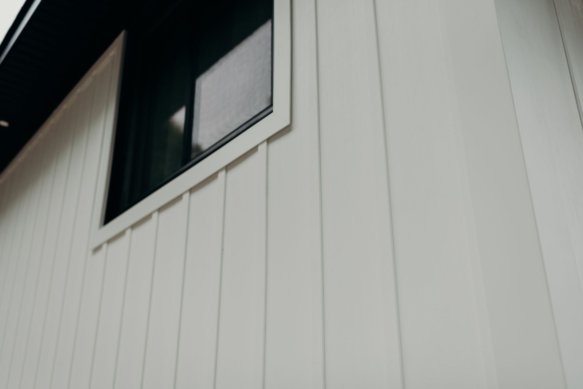 A close up of a white house with a black window.