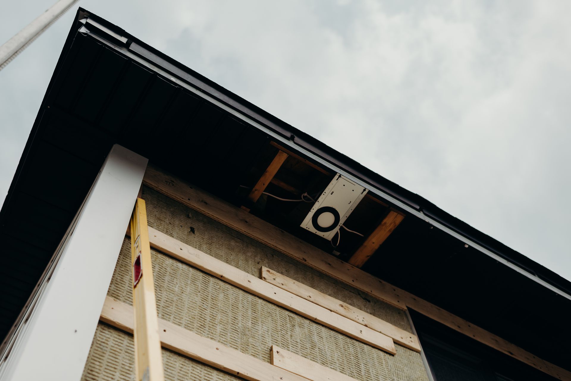 The roof of a house is being built and the gutters are being installed.