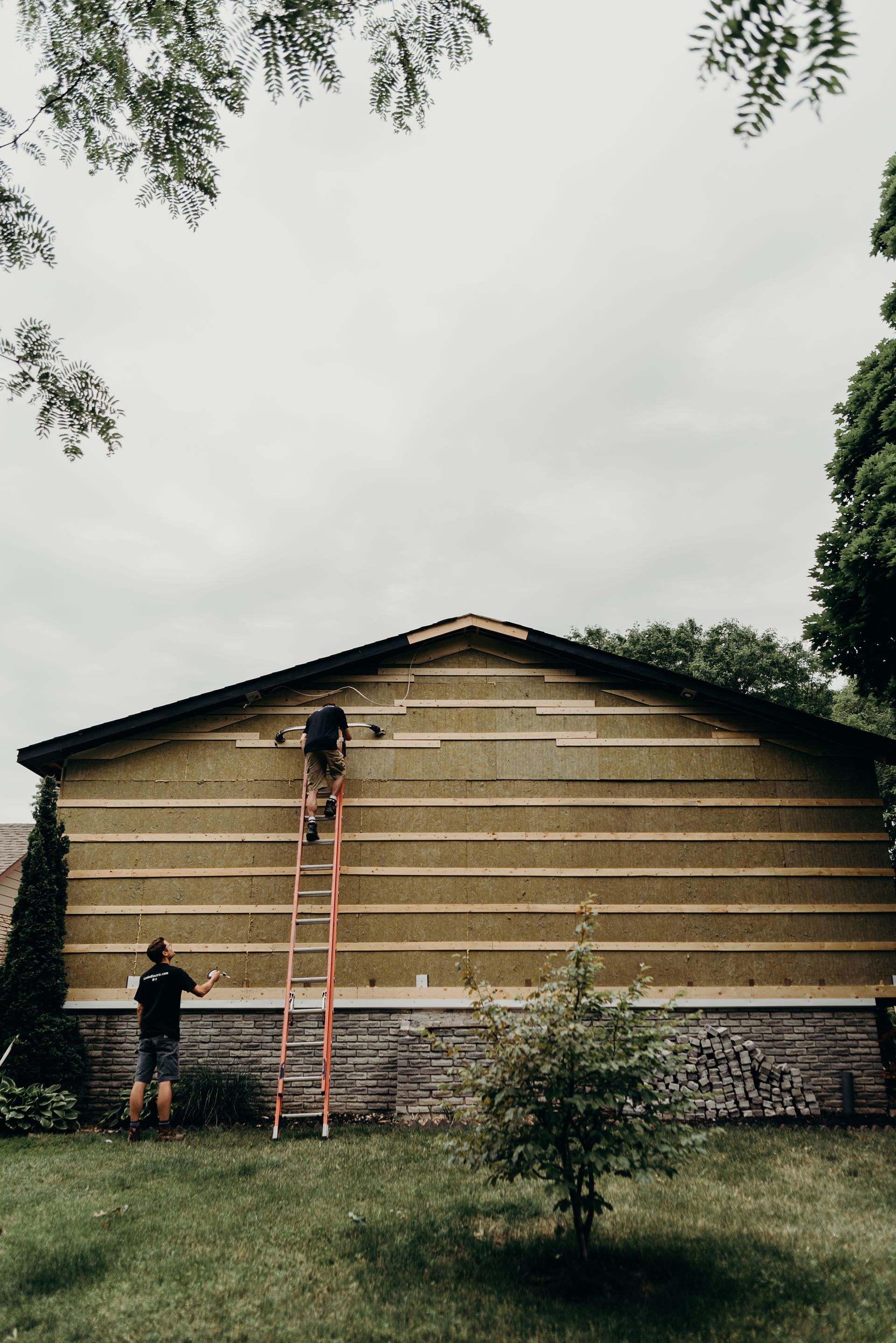 A man on a ladder is working on the side of a building.