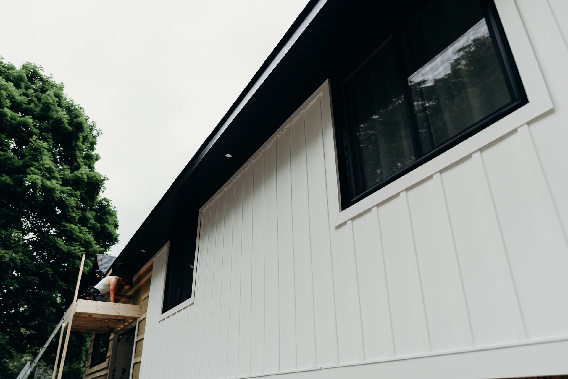A white house with black windows is being built.