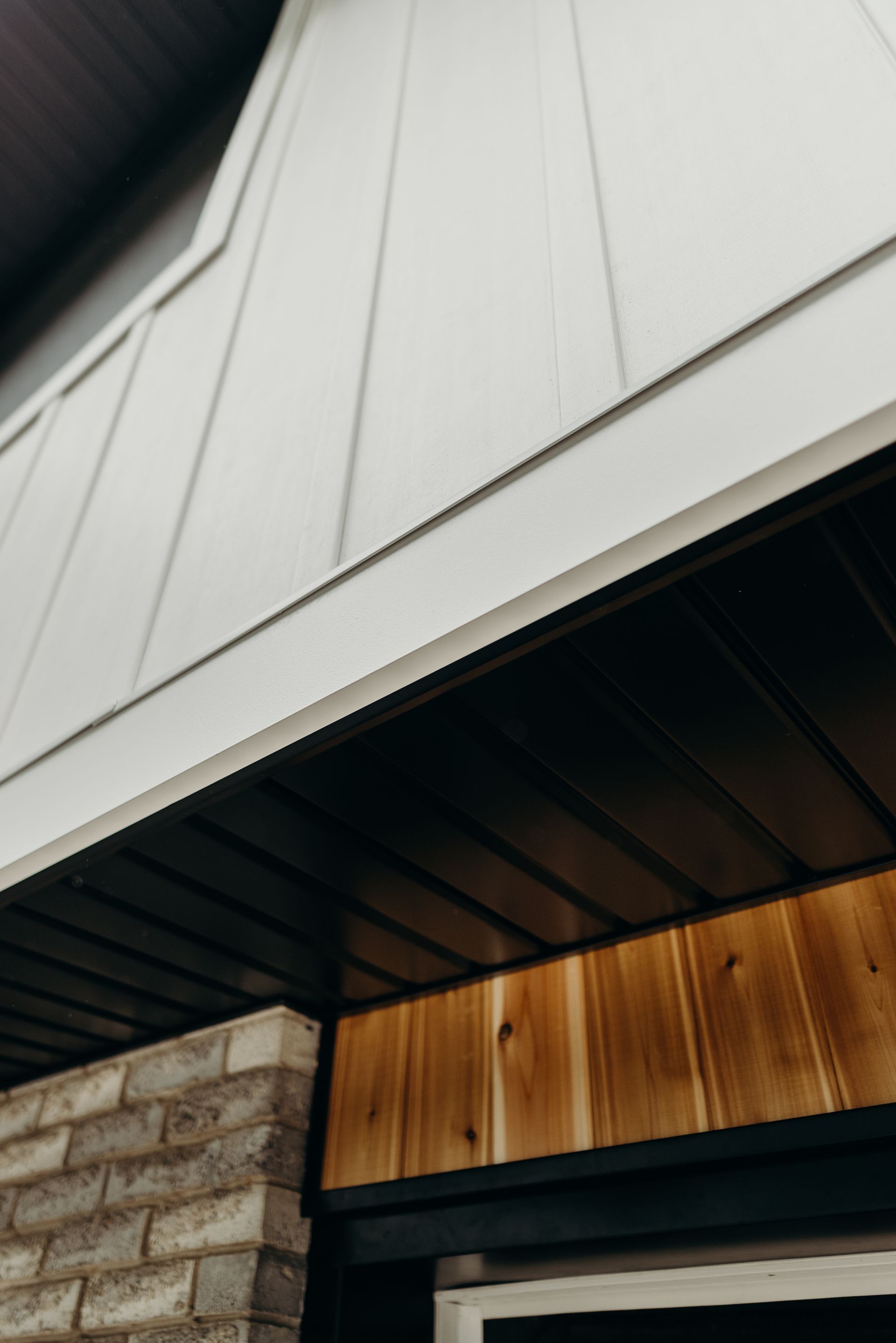 A close up of a house with a white siding and a wooden door.