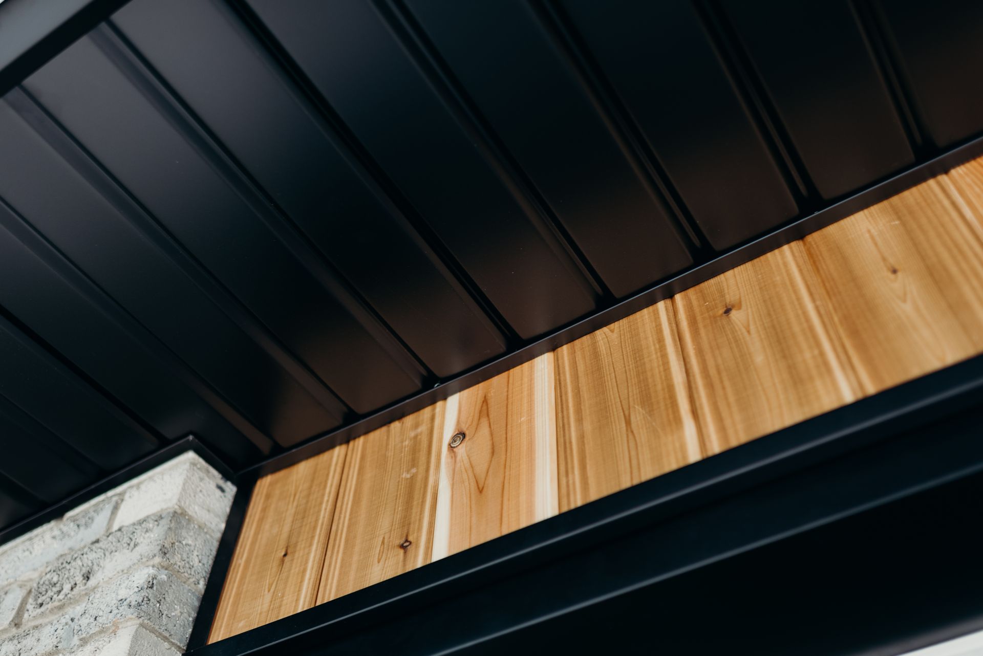 A close up of a black roof with a wooden trim.