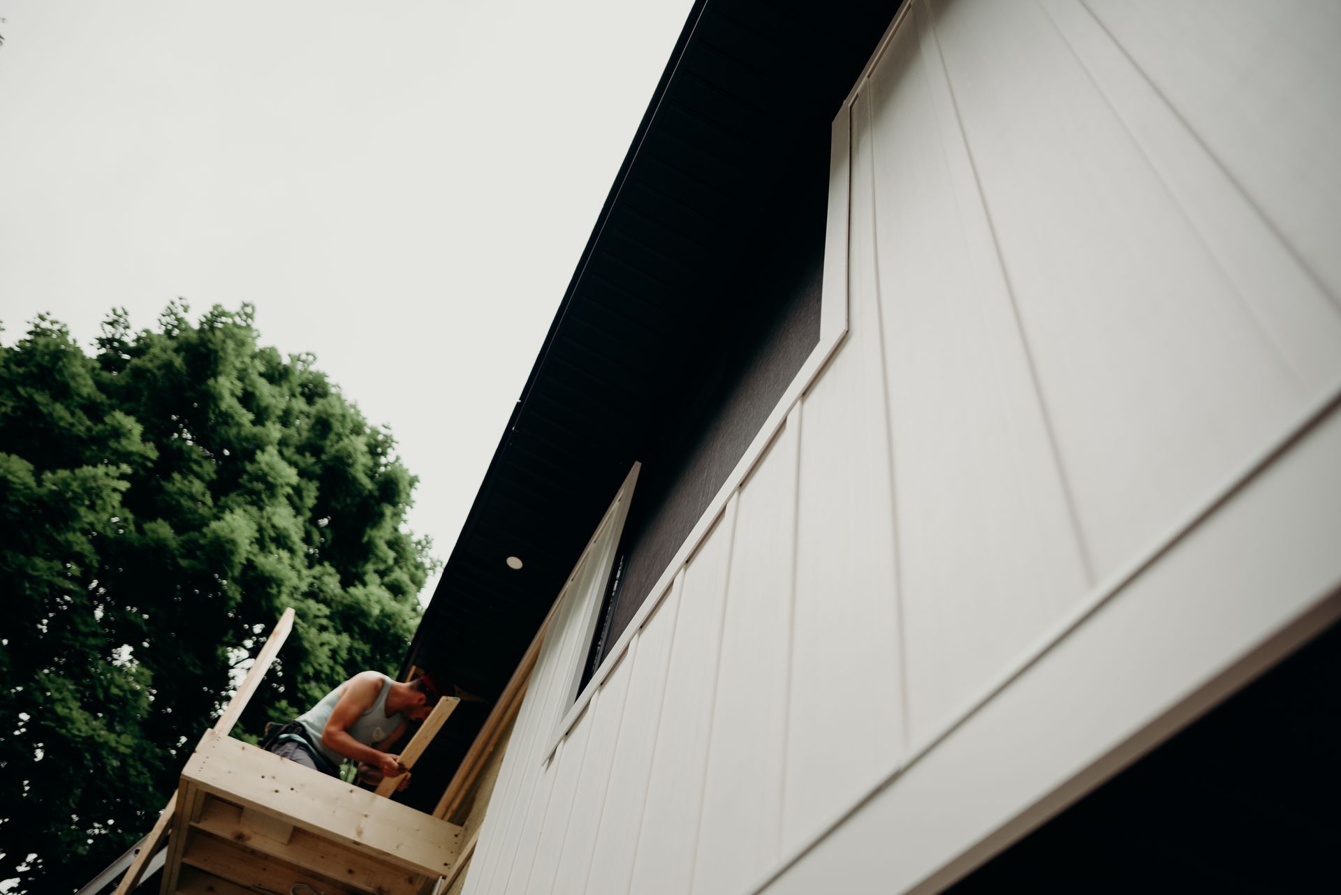 A man is working on the side of a house.