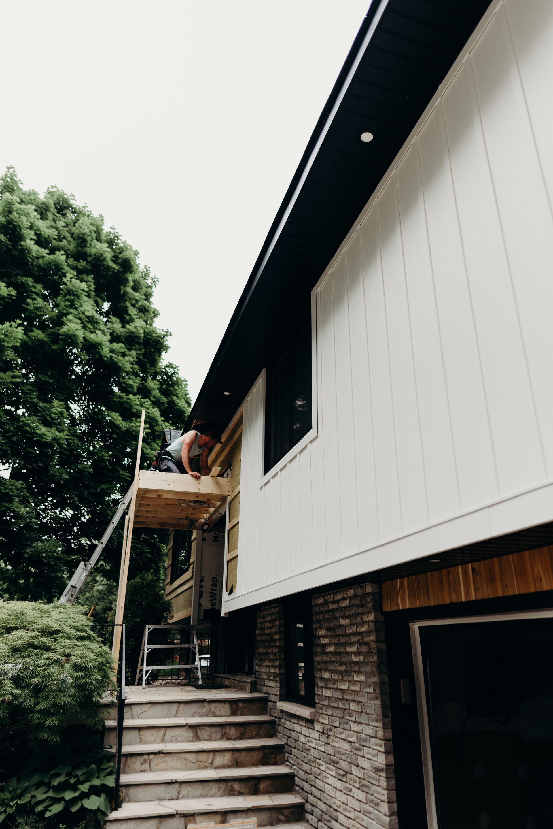A man is working on the side of a house.