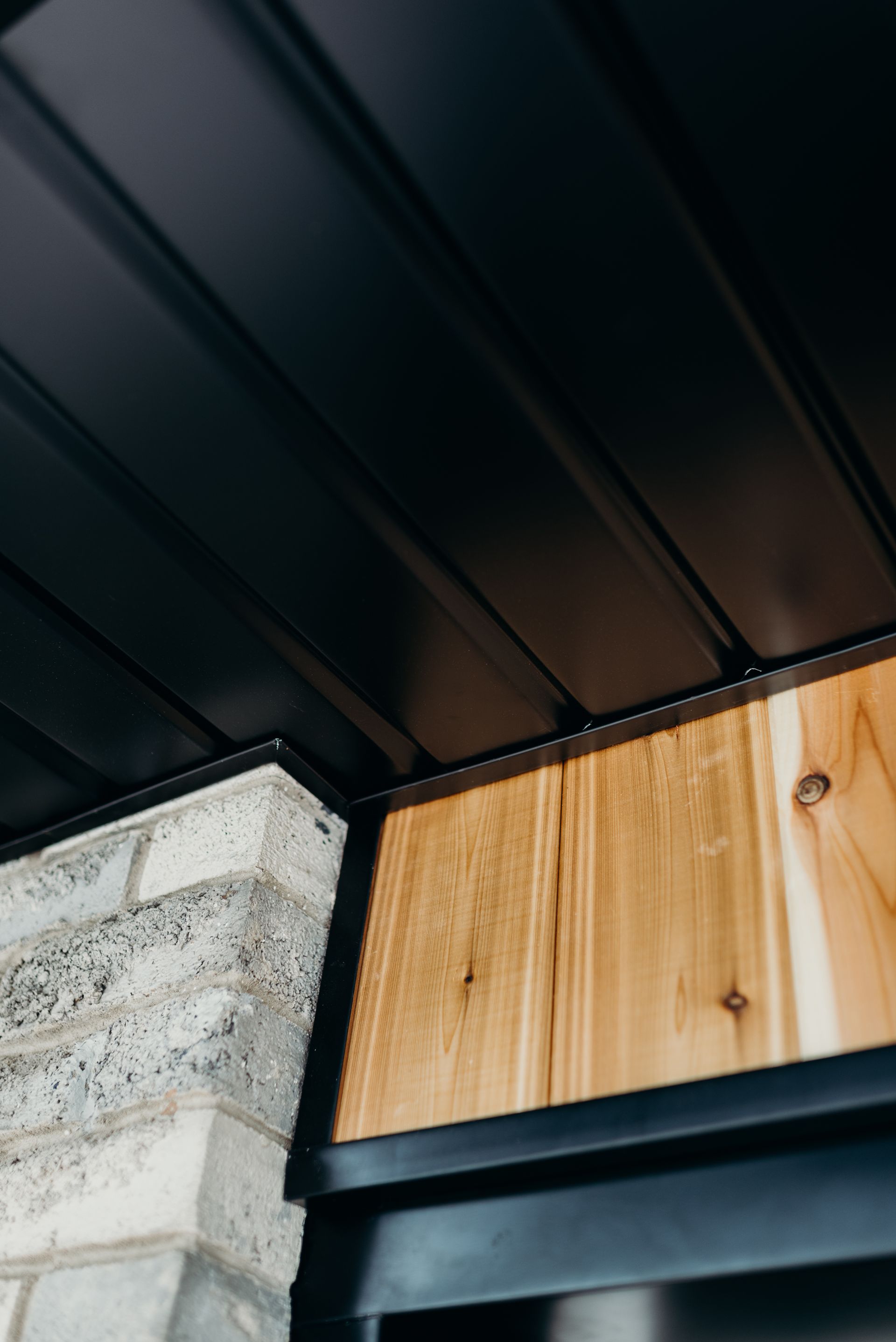 A black ceiling with a wooden trim and a brick wall