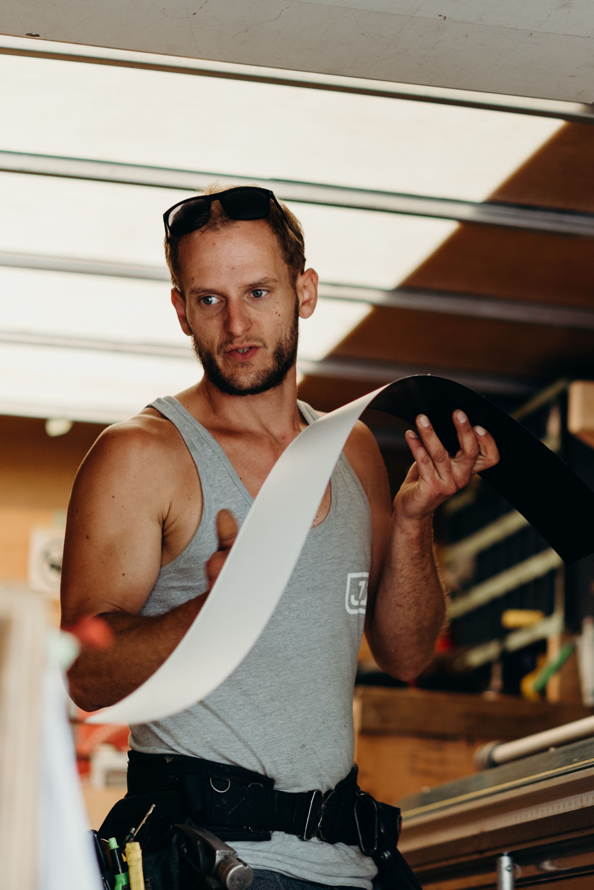 A man in a tank top is holding a piece of paper in his hand.