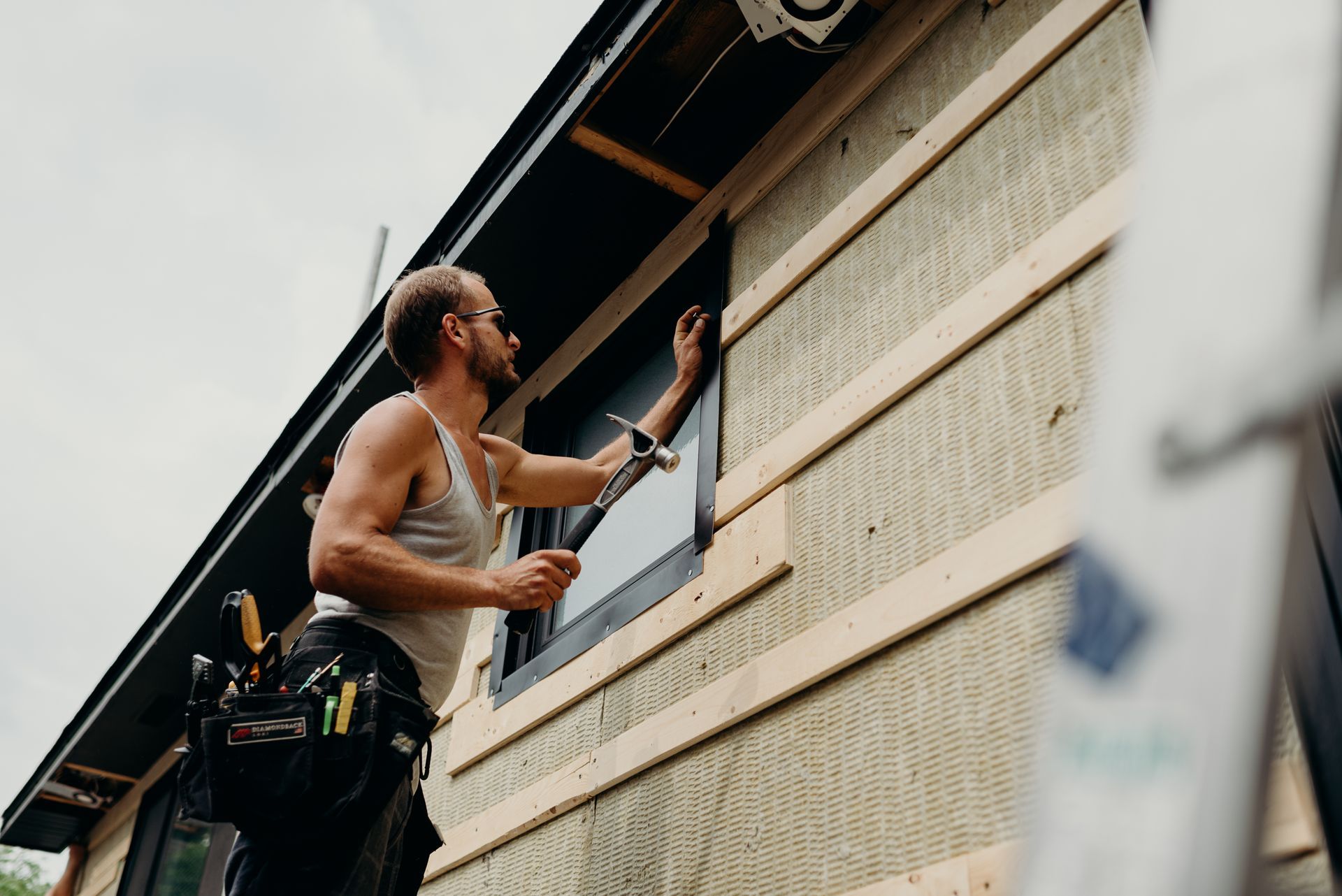 A man is installing a window on the side of a building.