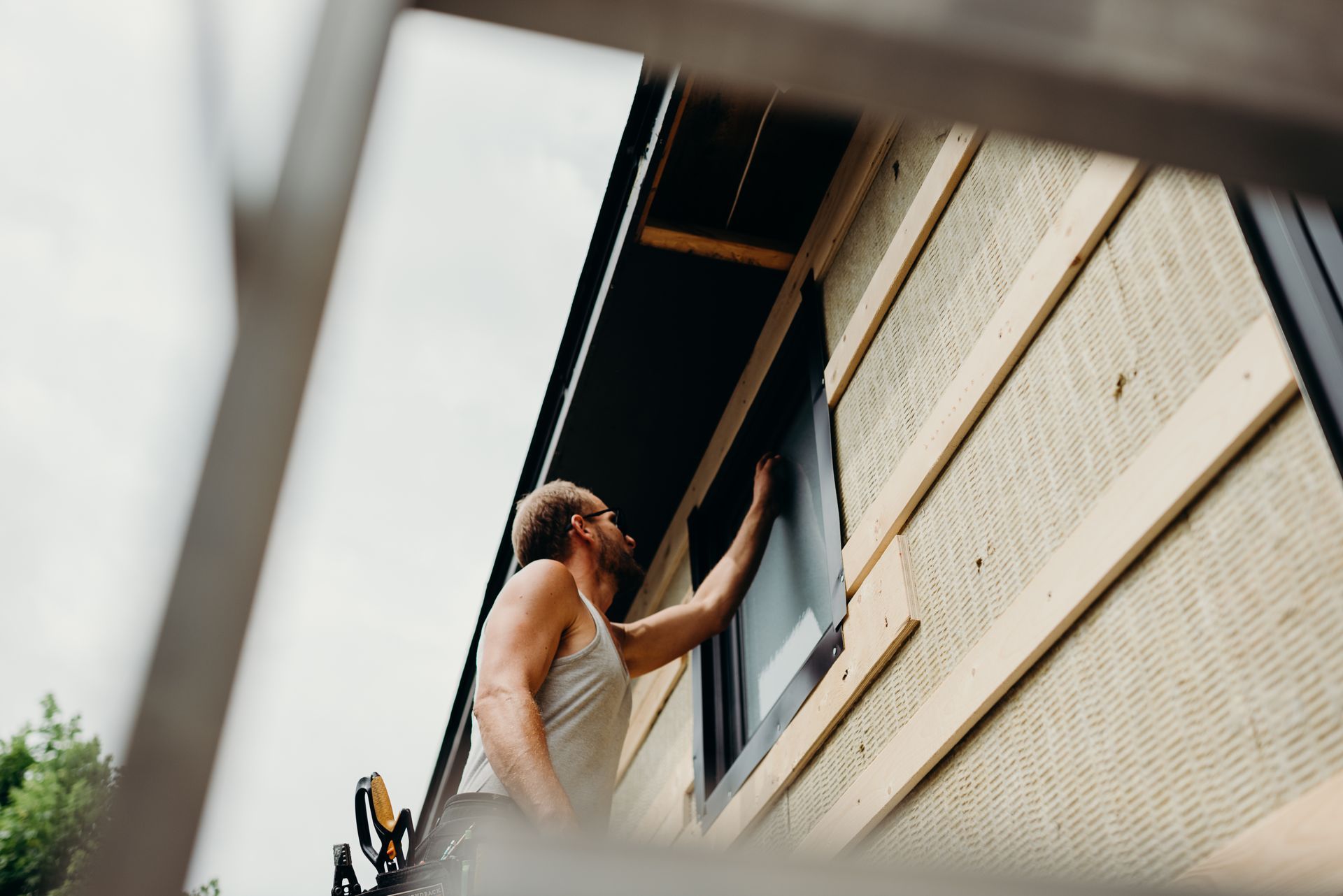 A man is fixing a window on the side of a house.