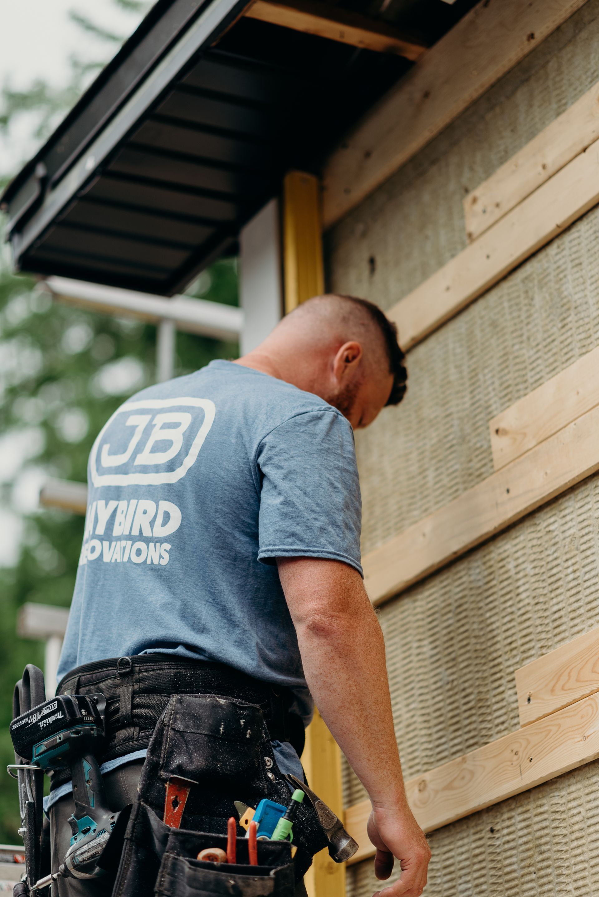 A man is working on the side of a house.