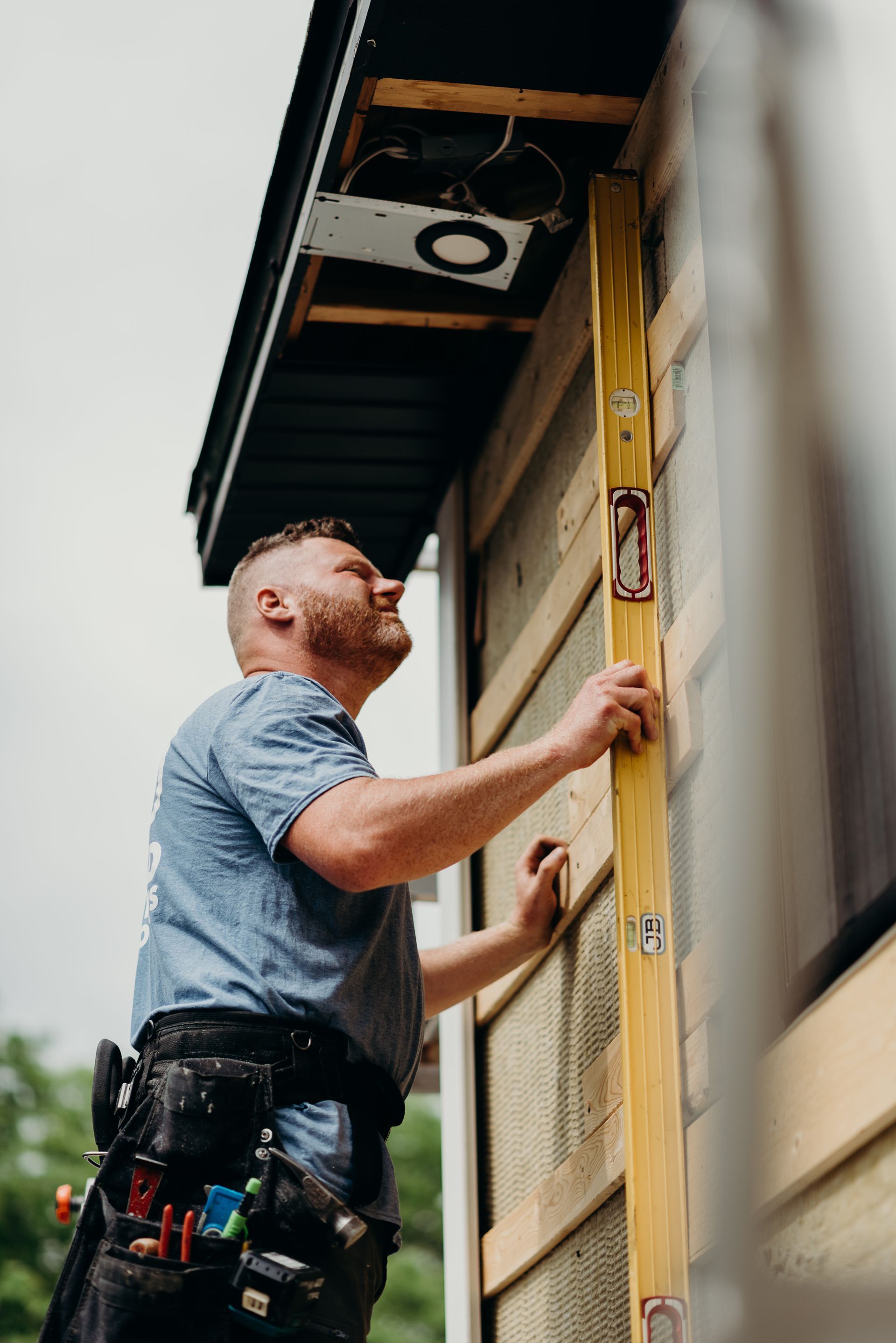 A man is using a level to measure the height of a building.
