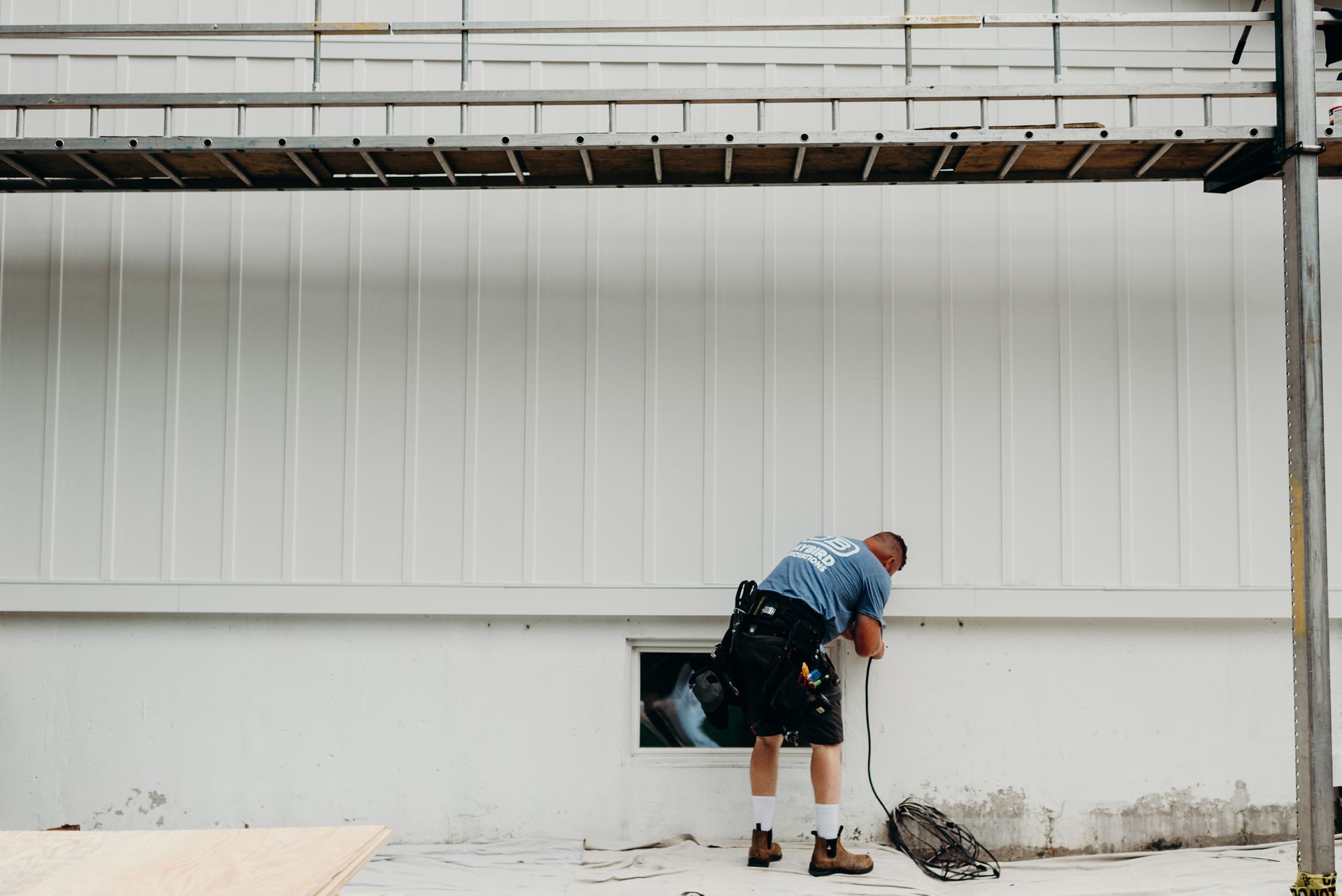 A man in a kilt is standing in front of a white building.