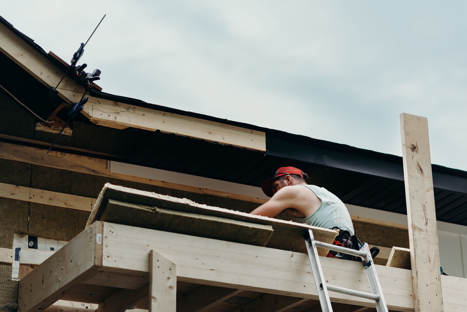 A man on a ladder is working on the roof of a building.
