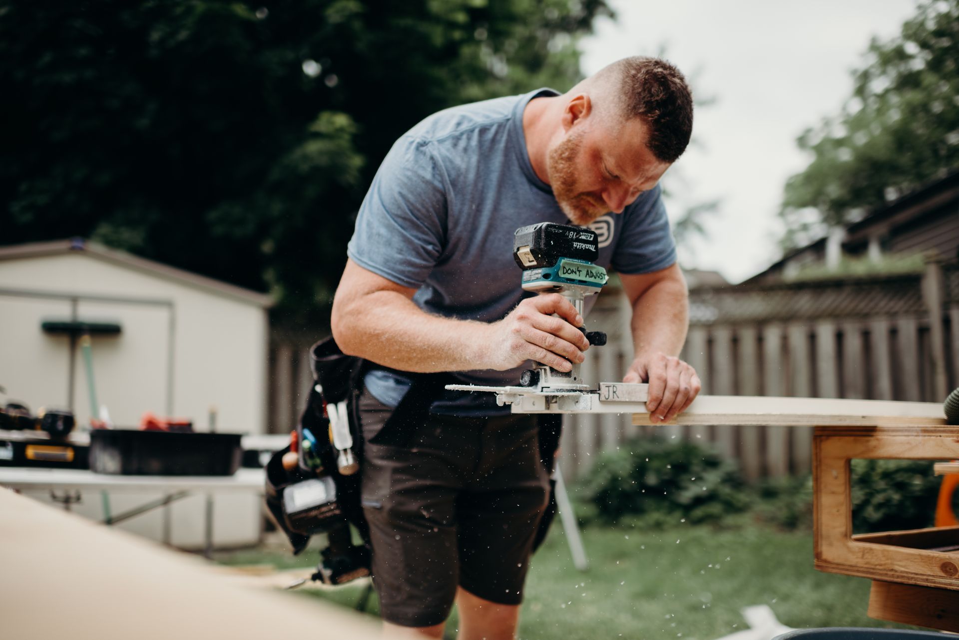 A man is using a router to cut a piece of wood.