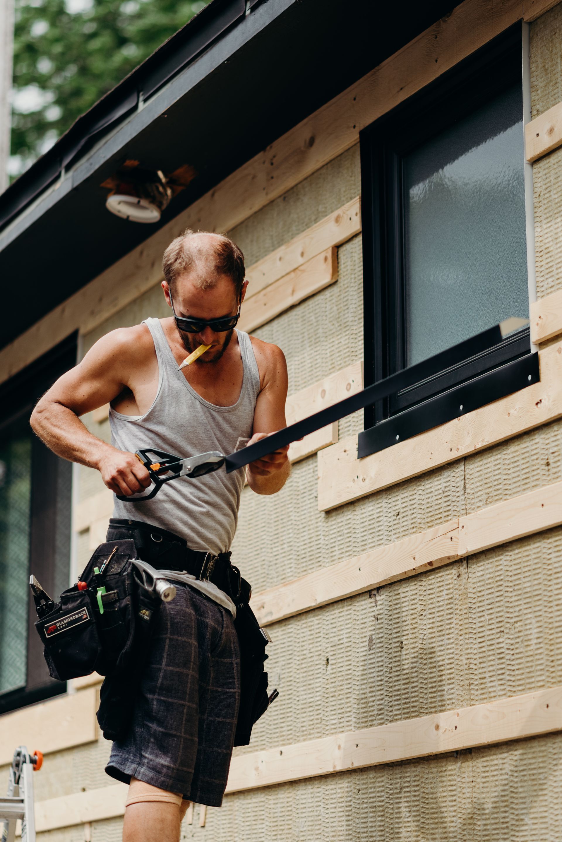A man is measuring a window with a tape measure.