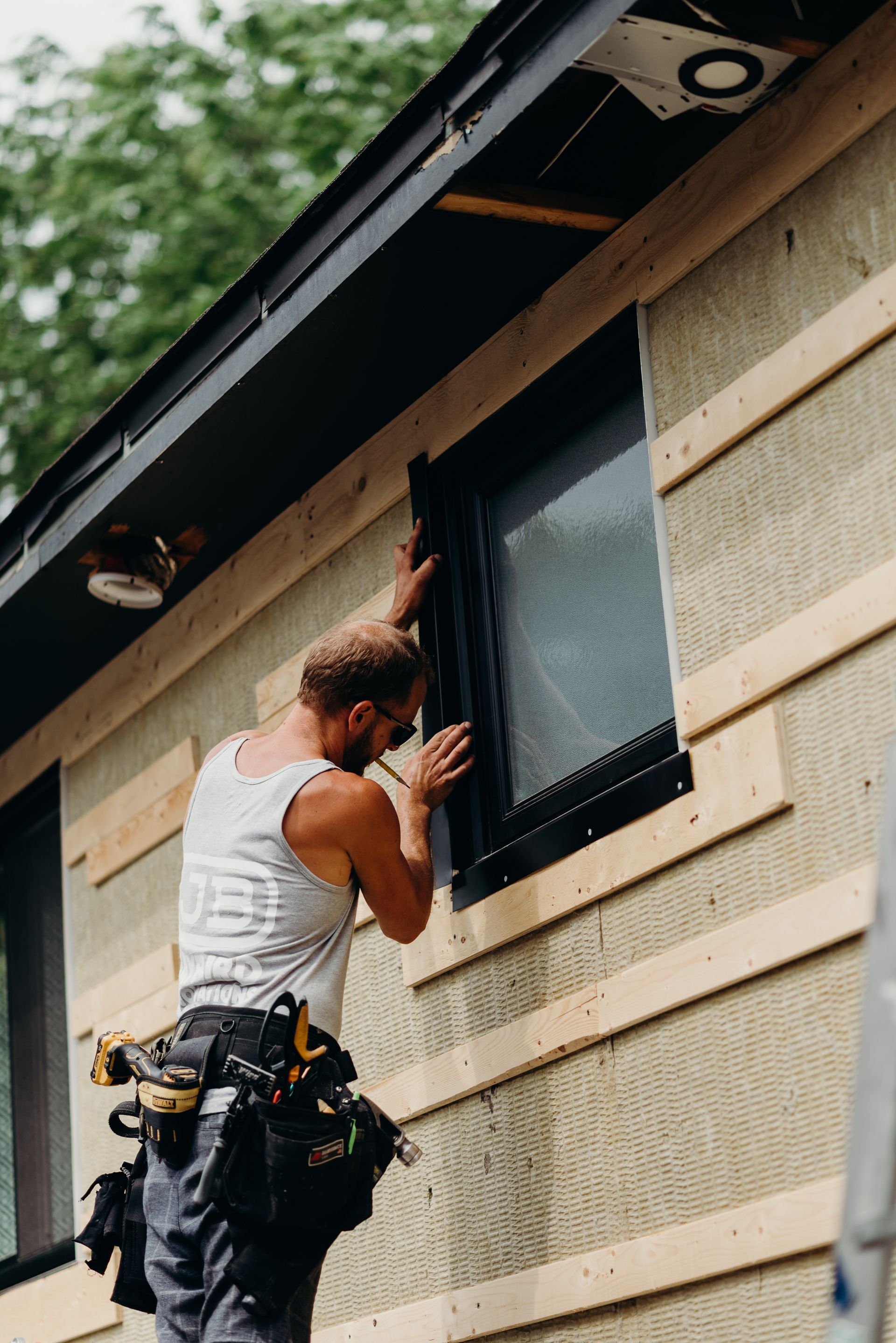A man is installing a window on the side of a building.