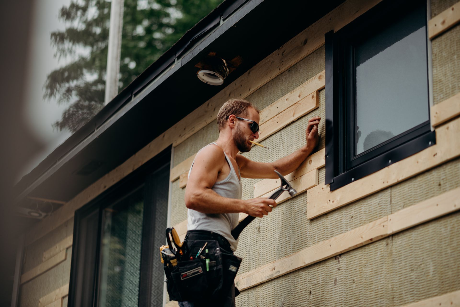 A man is fixing a window on the side of a house.