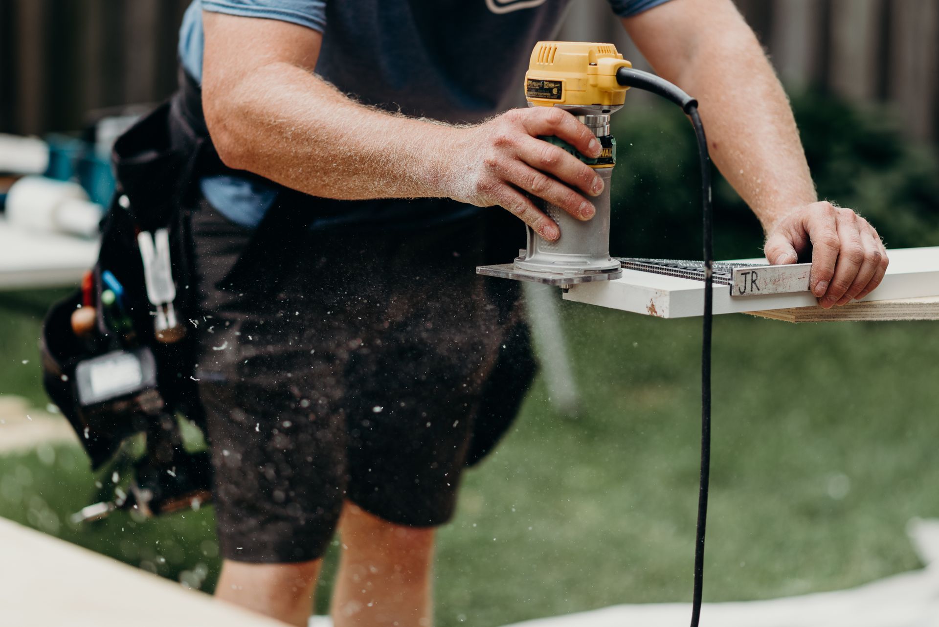 A man is using a router to cut a piece of wood.