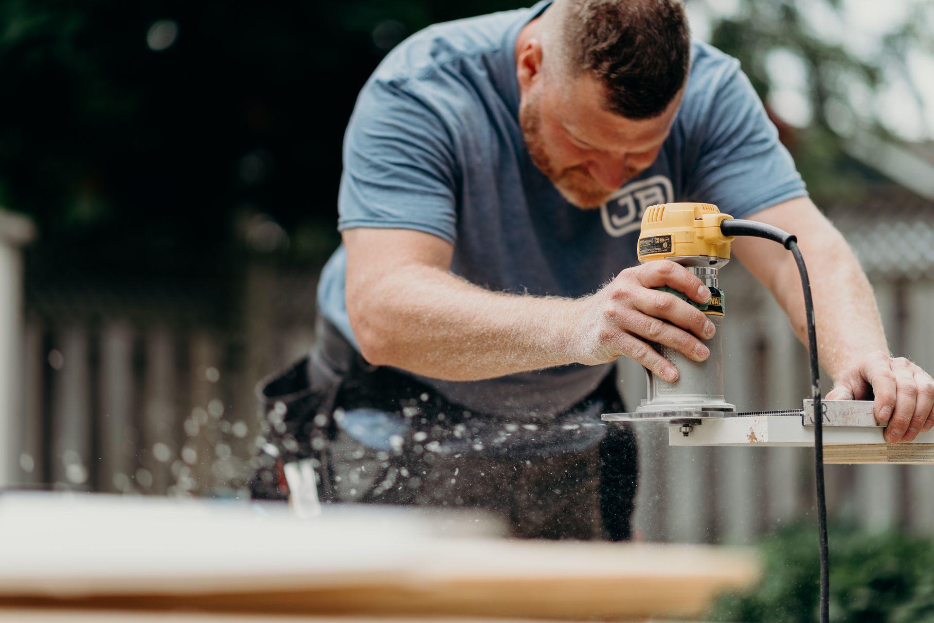 A man is using a router to cut a piece of wood.