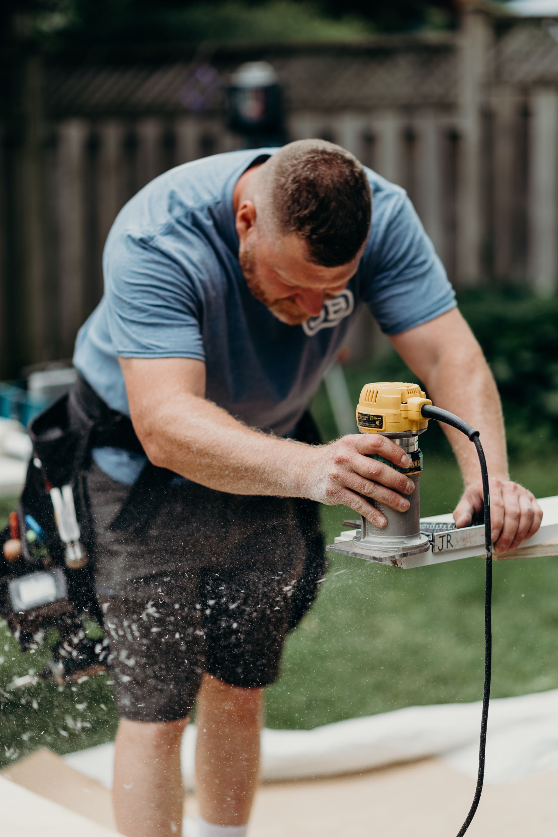 A man is using a router to cut a piece of wood.