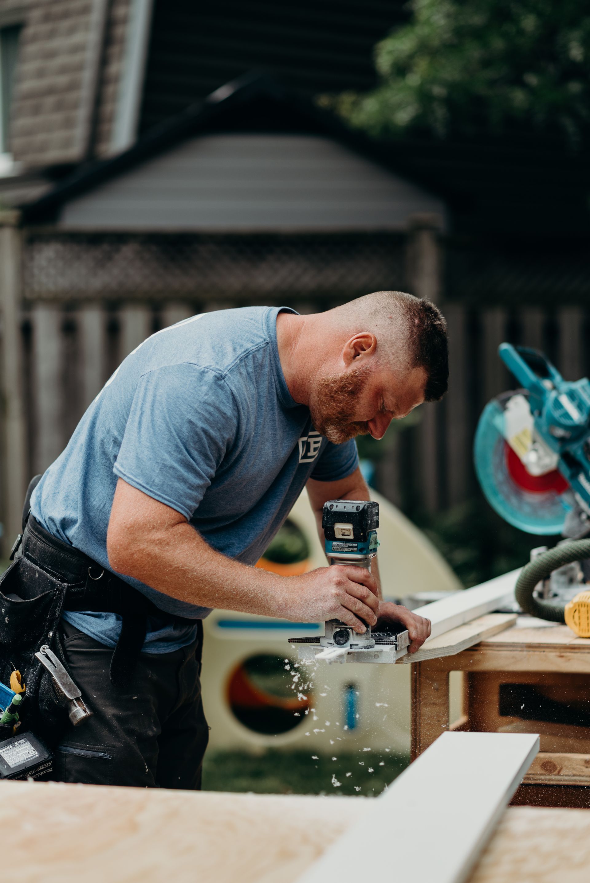 A man is using a router to cut a piece of wood.