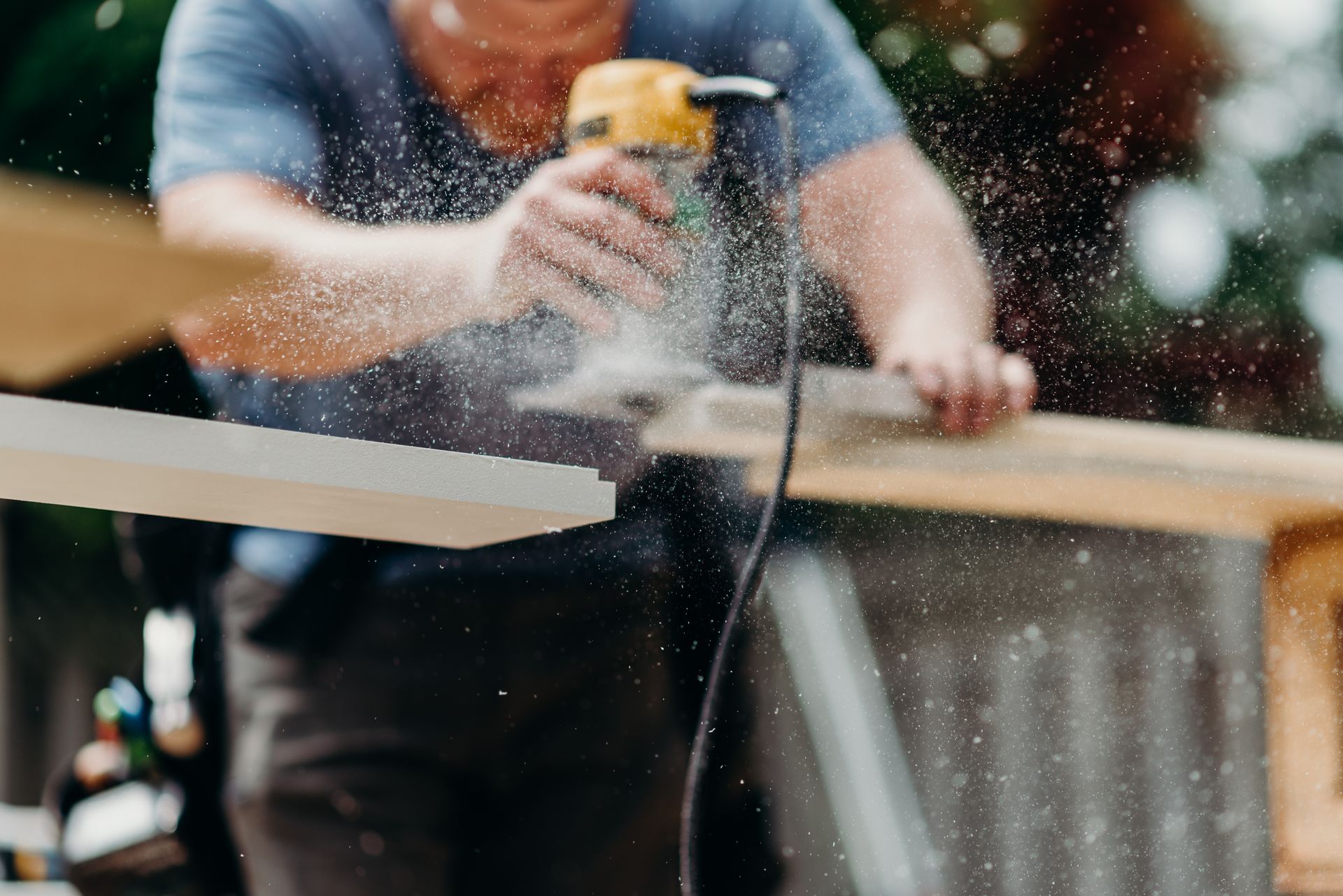 A man is sanding a piece of wood with a sander.