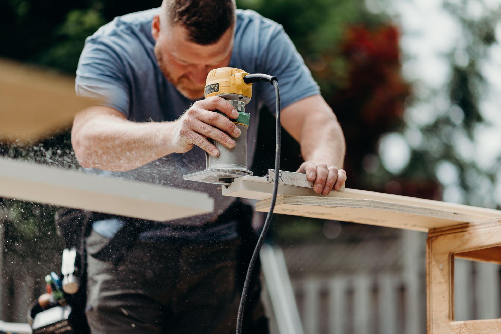 A man is using a router to cut a piece of wood.