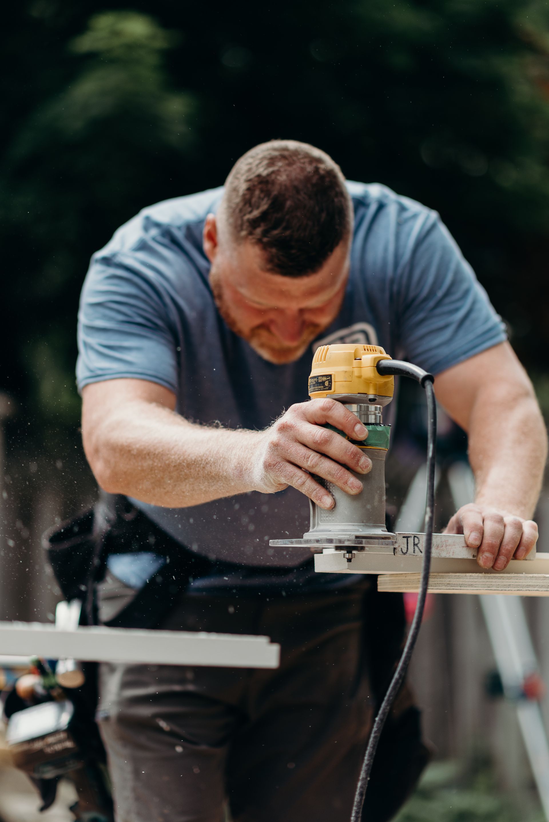 A man is using a router to cut a piece of wood.