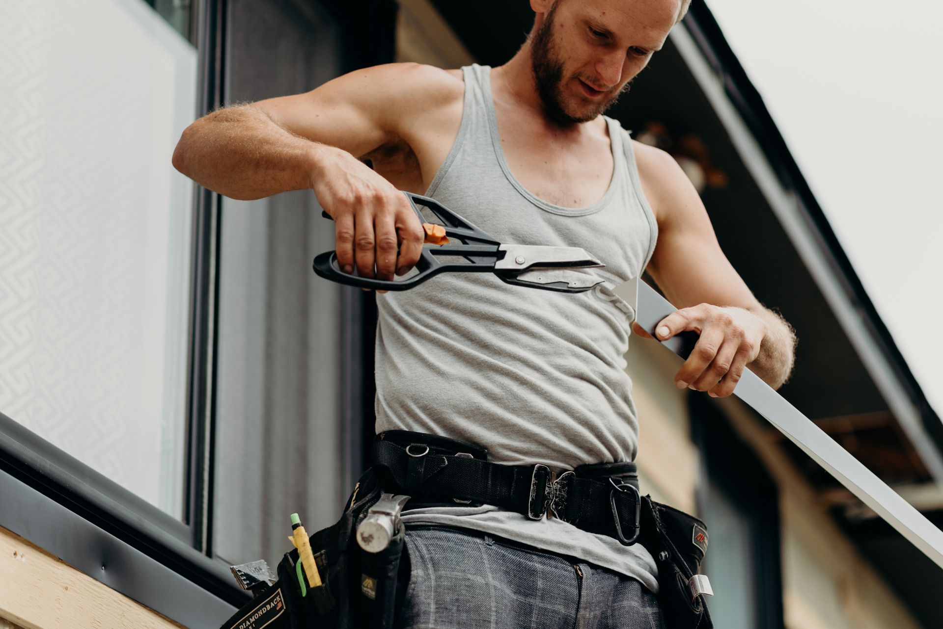 A man is cutting a piece of wood with a pair of scissors.