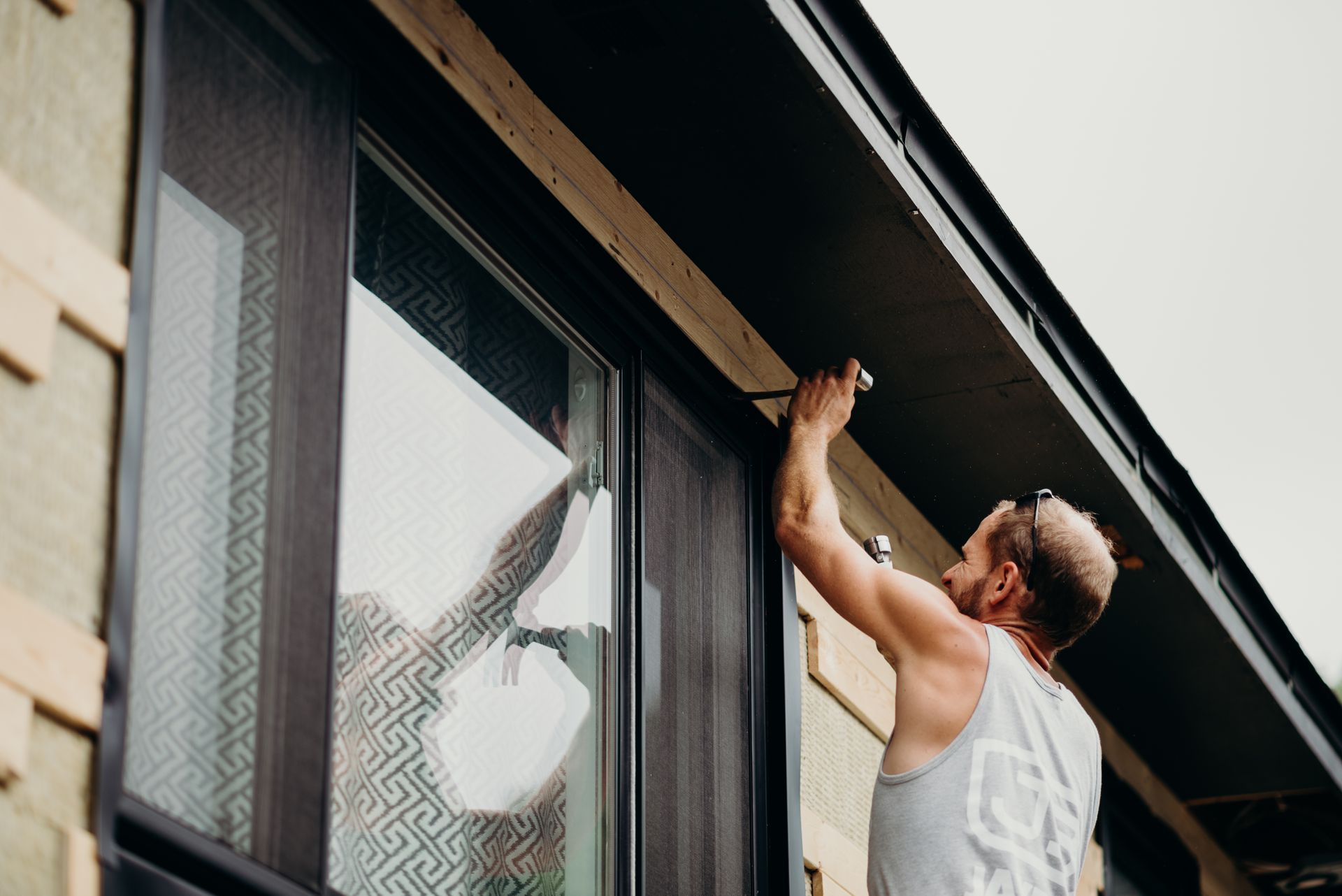 A man is measuring a window with a tape measure.