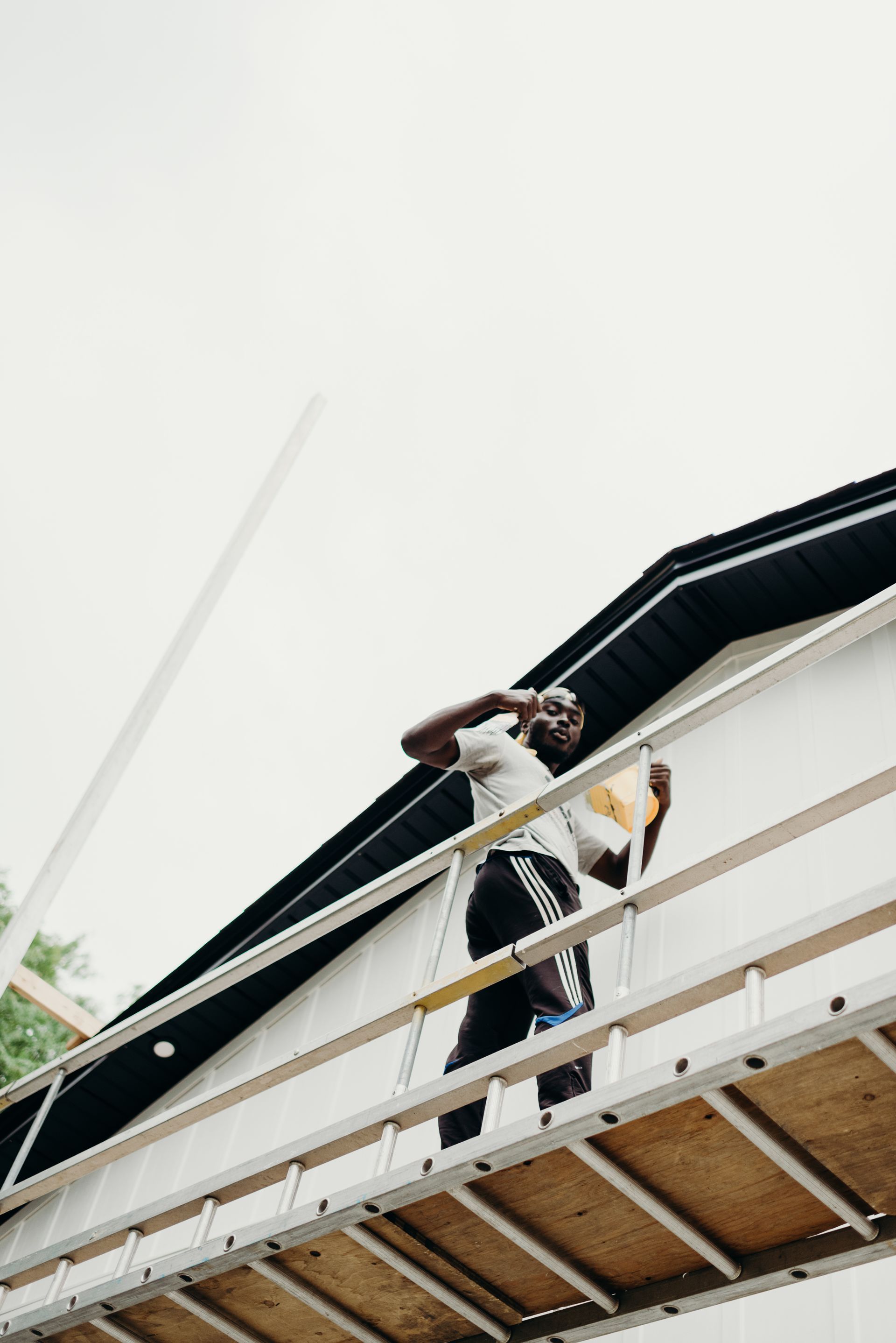 A man is standing on a ladder on the side of a building.