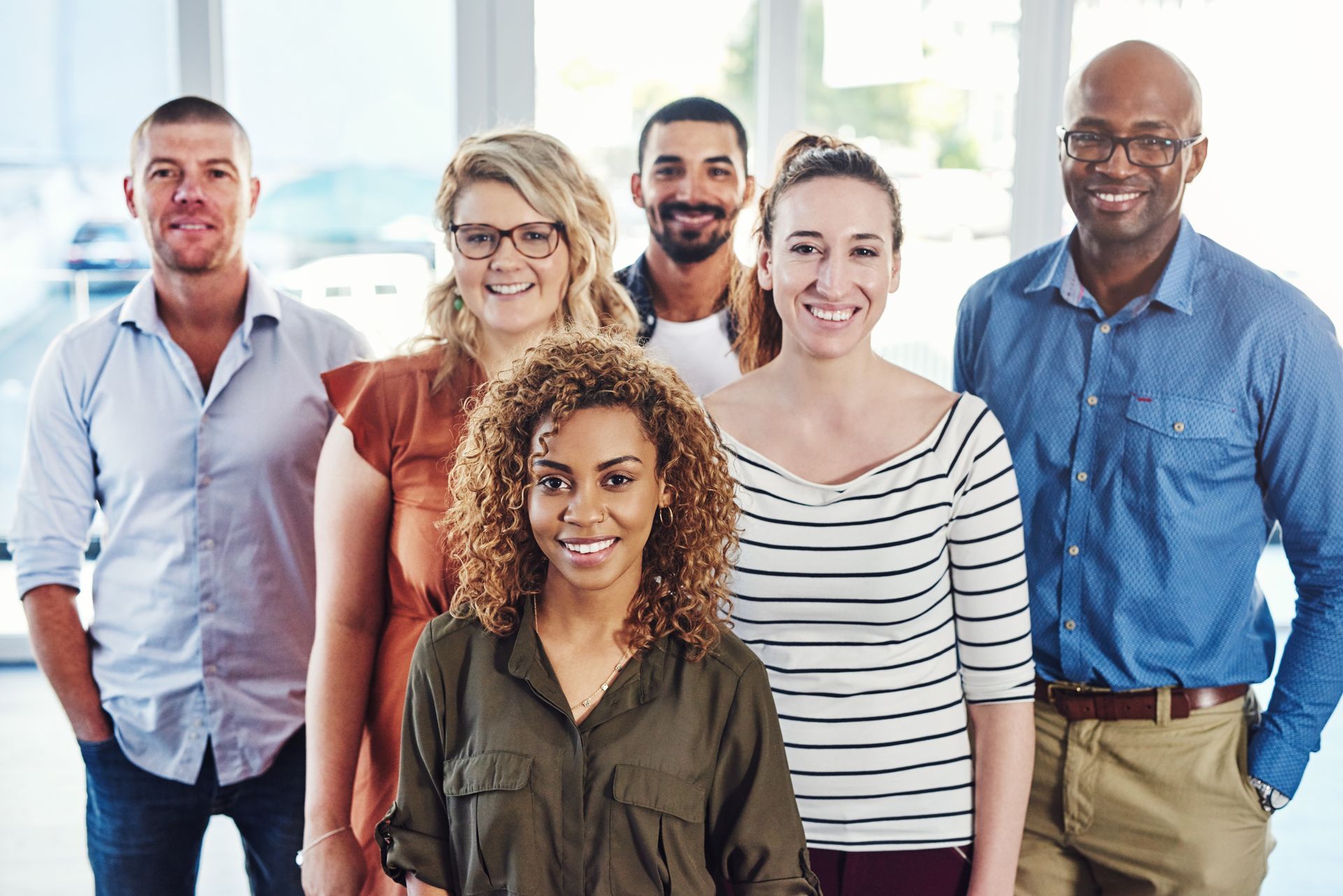 A group of people are standing next to each other and smiling for the camera.