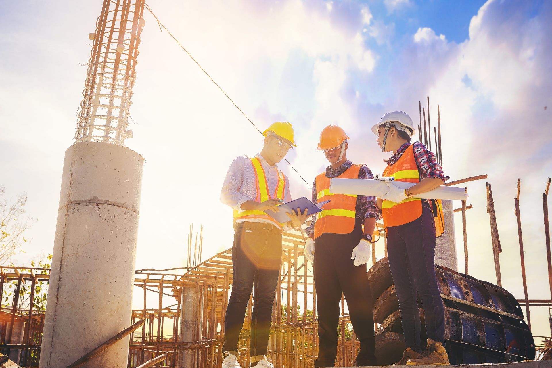 A group of construction workers are standing at a construction site looking at a blueprint.