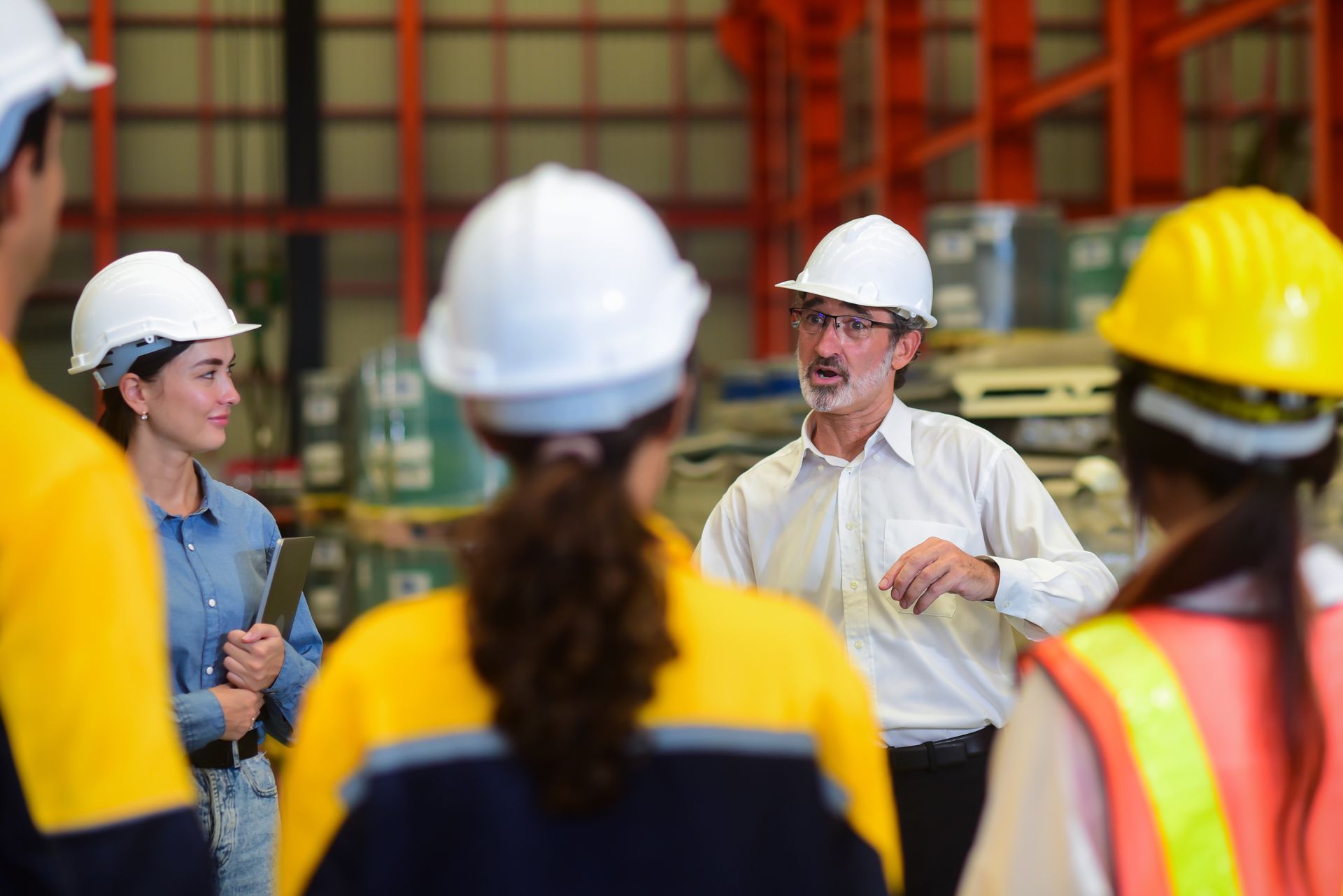 A group of construction workers are having a meeting in a warehouse.