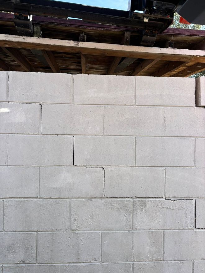 A close-up view of a newly built gray concrete block wall under a wooden roof structure.
