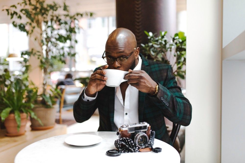 a man sits at a table drinking a cup of coffee